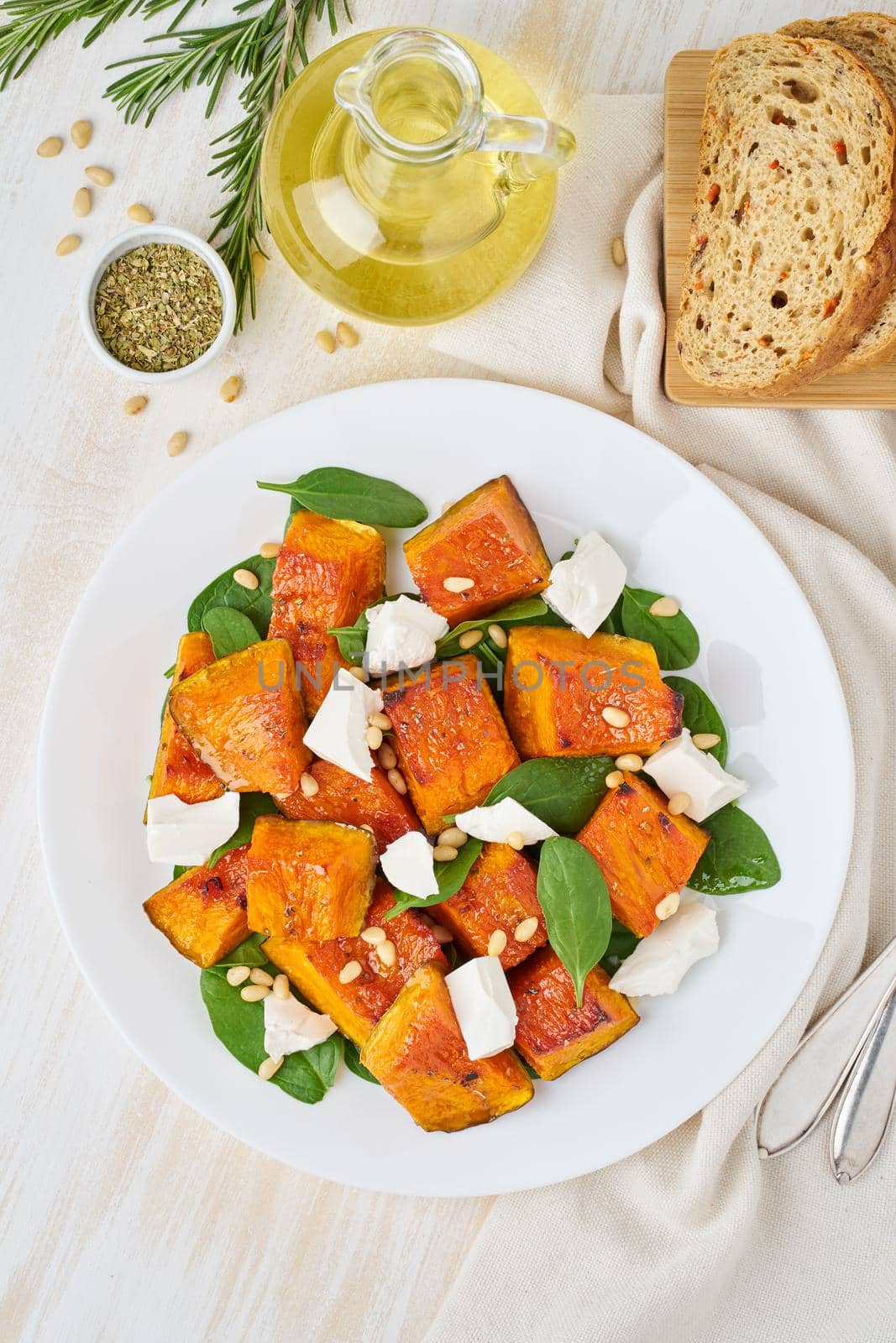 Salad with roasted pumpkin, feta cheese, spinach, nuts with honey and seasonings, top view