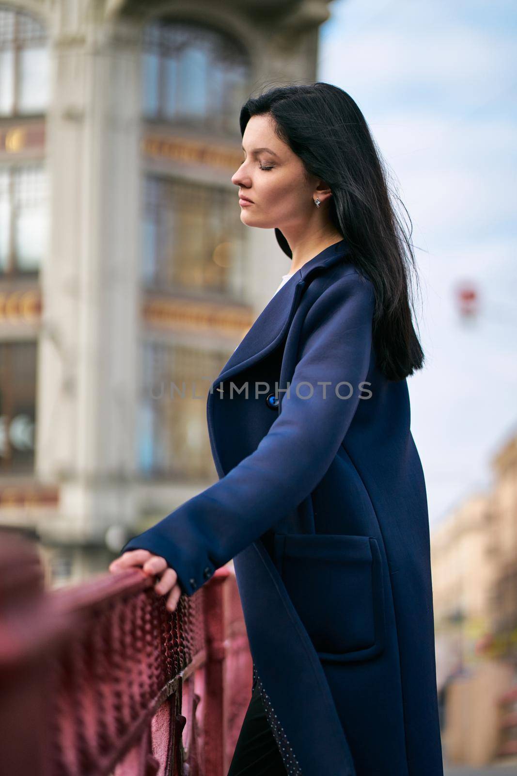 Portrait close-up of beautiful intelligent brunette who walks down street of St. Petersburg in city center. Charming thoughtful woman with long dark hair wanders alone, immersed in thoughts by NataBene