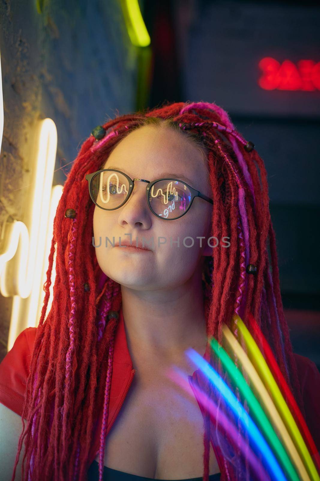Girl in neon lights at party in nightclub, beautiful woman in sunglasses, with long pink hair, with dreadlocks pigtails, bright and stylish in the glow of neon signs, vertical, close up