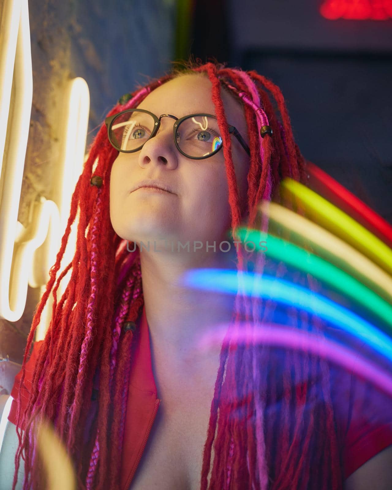 Girl in neon lights at party in nightclub, beautiful woman in sunglasses, with long pink hair, with dreadlocks pigtails, bright and stylish in the glow of neon signs