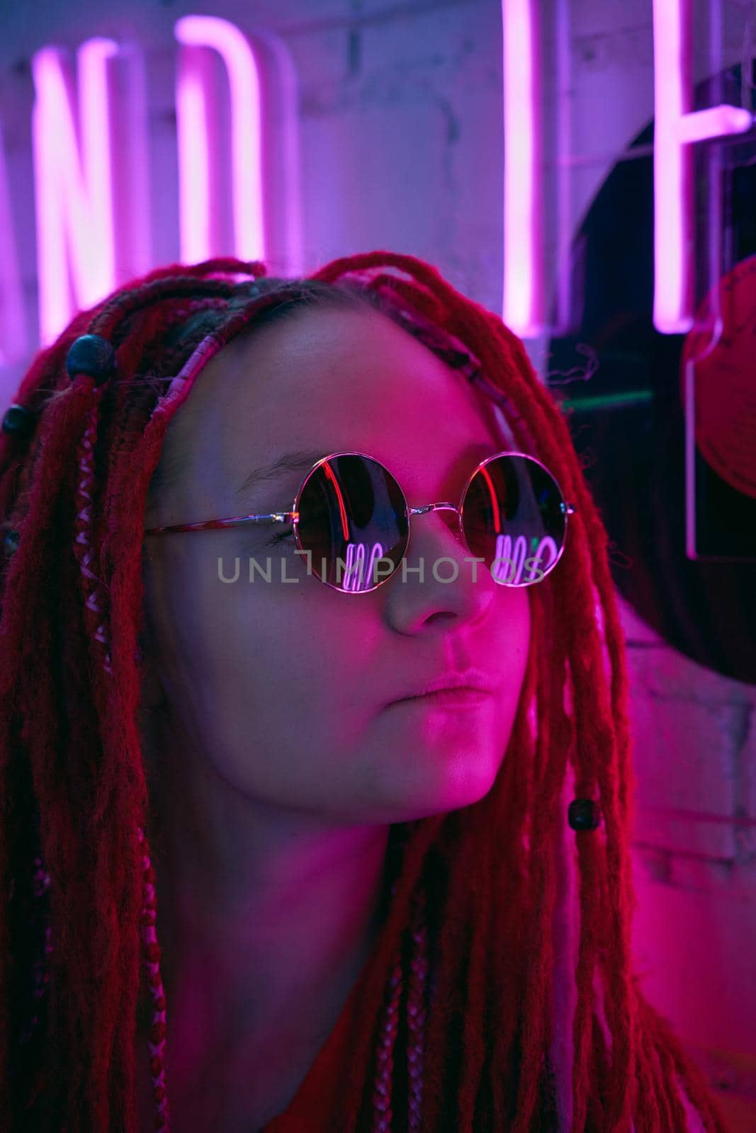Girl in neon lights at party in nightclub, beautiful woman in sunglasses, with long pink hair, with dreadlocks pigtails, bright and stylish in the glow of neon signs, vertical, close up