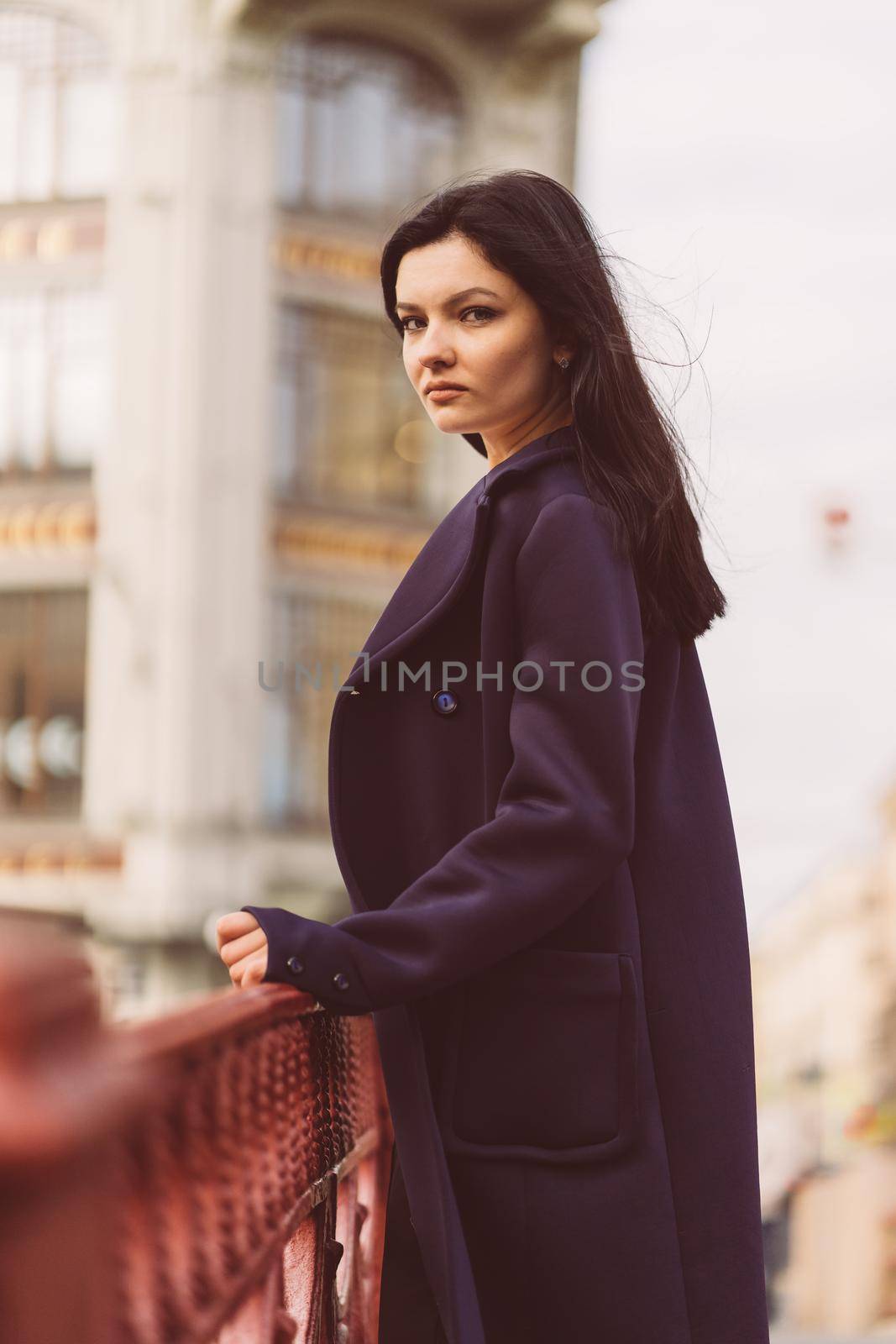 Portrait close-up of beautiful intelligent brunette who walks down street of St. Petersburg in city center. Charming thoughtful woman with long dark hair wanders alone, immersed in thoughts, vertical