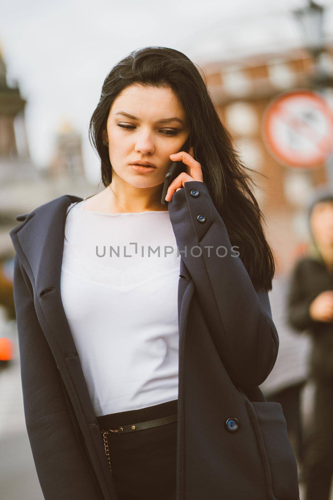 Woman with long hair talking on phone. Autumn or winter, girl in outdoor. Beautiful intelligent brunette in street of Saint-Petersburg in city center, copy space by NataBene
