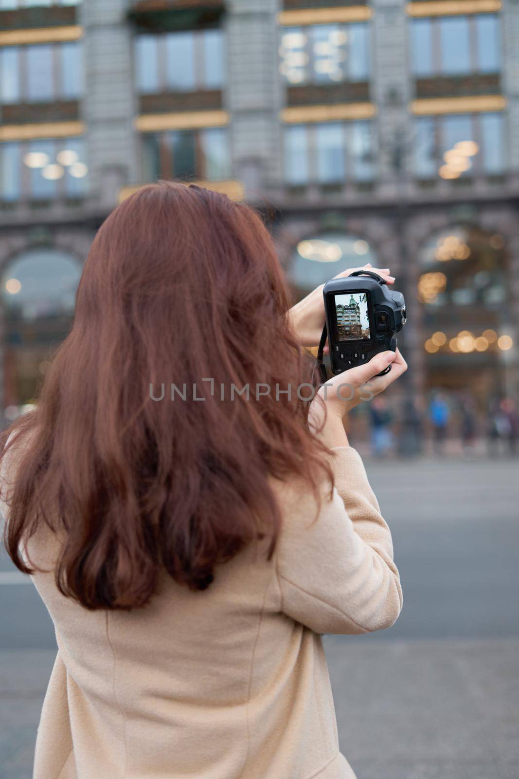 Unrecognizable person standing with his back turned and photographs sights, woman with long thick dark hair, tourist in center of St. Petersburg. Focus on camera by NataBene