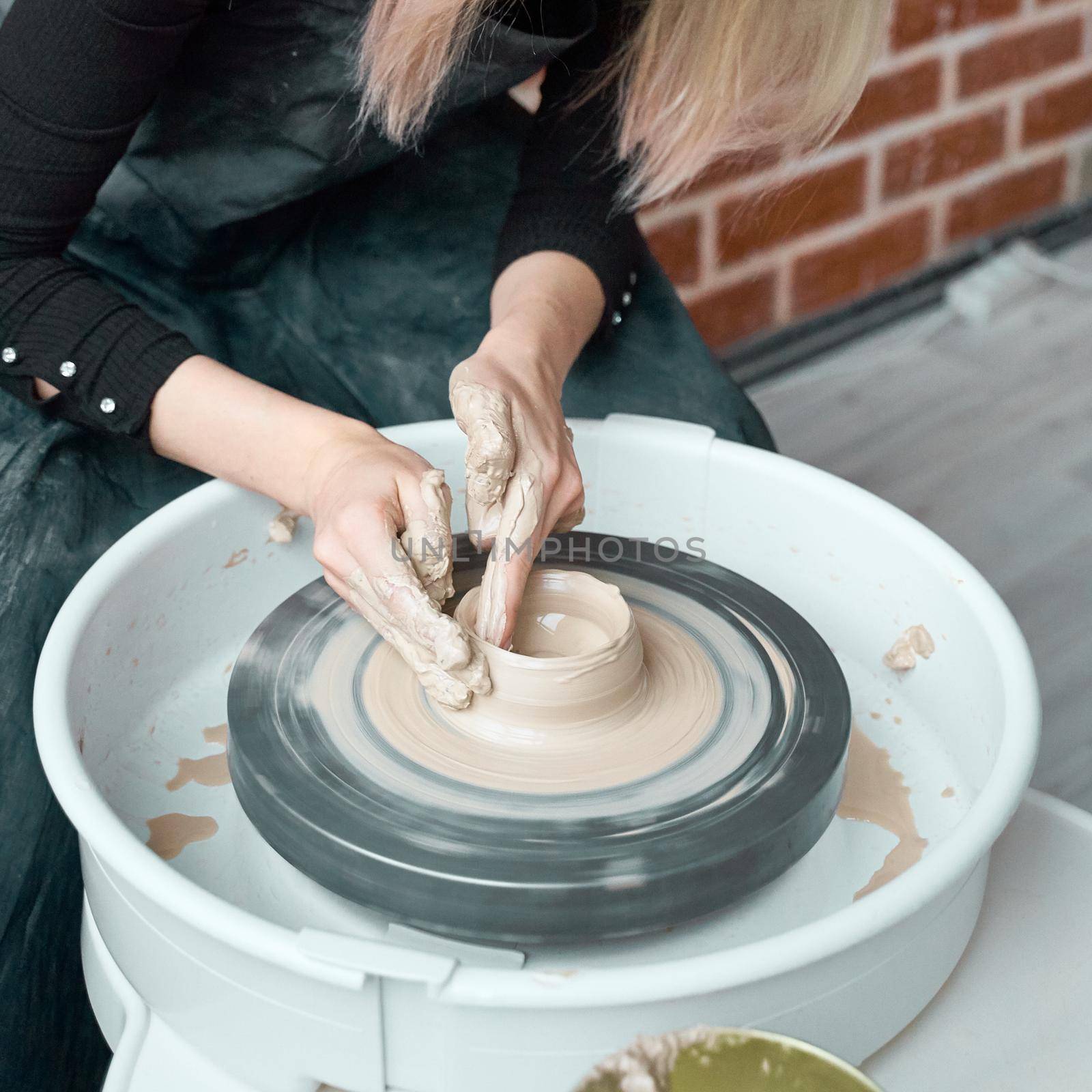 Woman making ceramic pottery on wheel, hands close-up, creation of ceramic ware. Handwork, craft, manual labor, buisness. Earn extra money, turning hobbies into cash and turning passion into a job