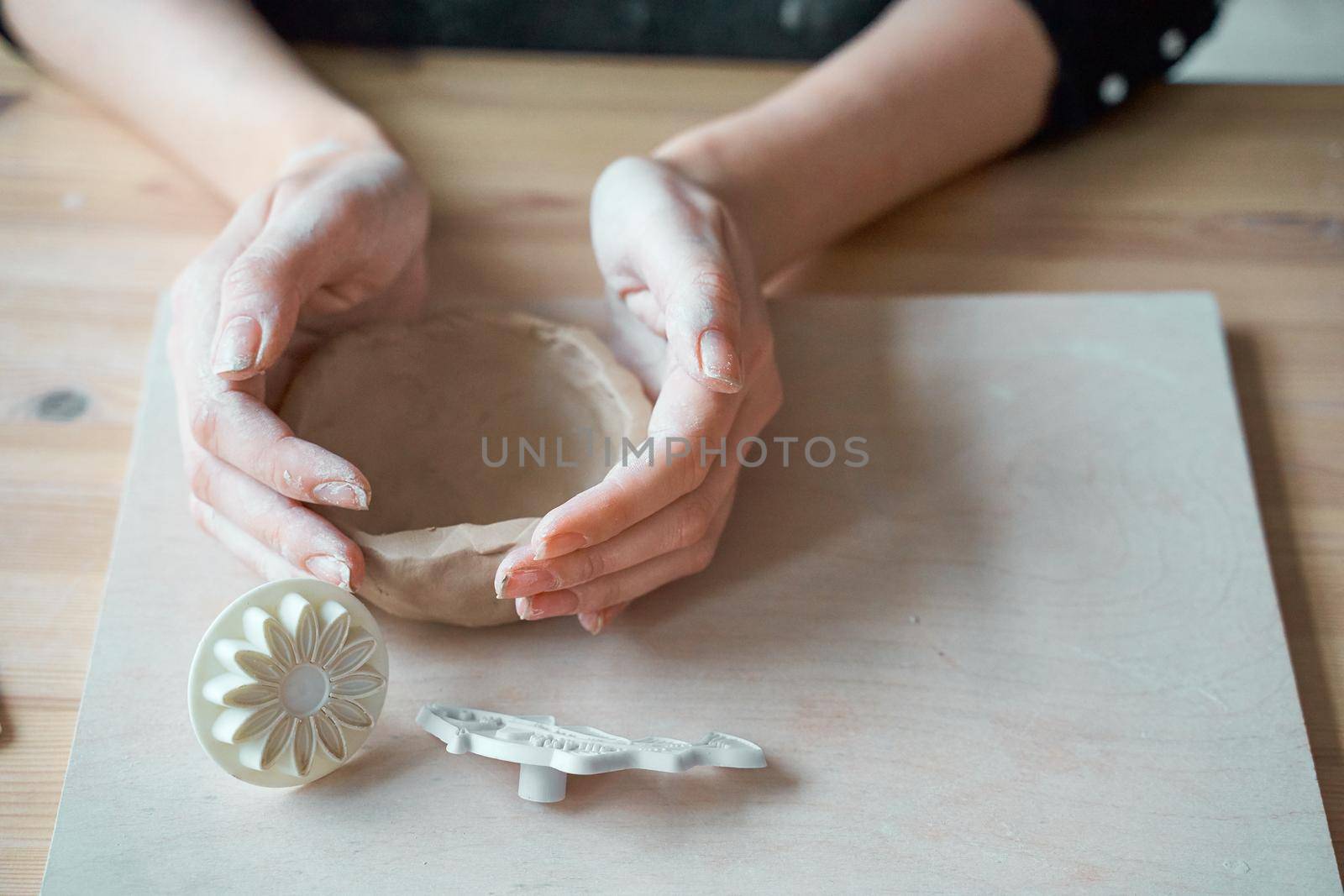 Woman making pottery, hands closeup, blurred background, focus on potters, palms with pottery. Turning passion into a job, copy space
