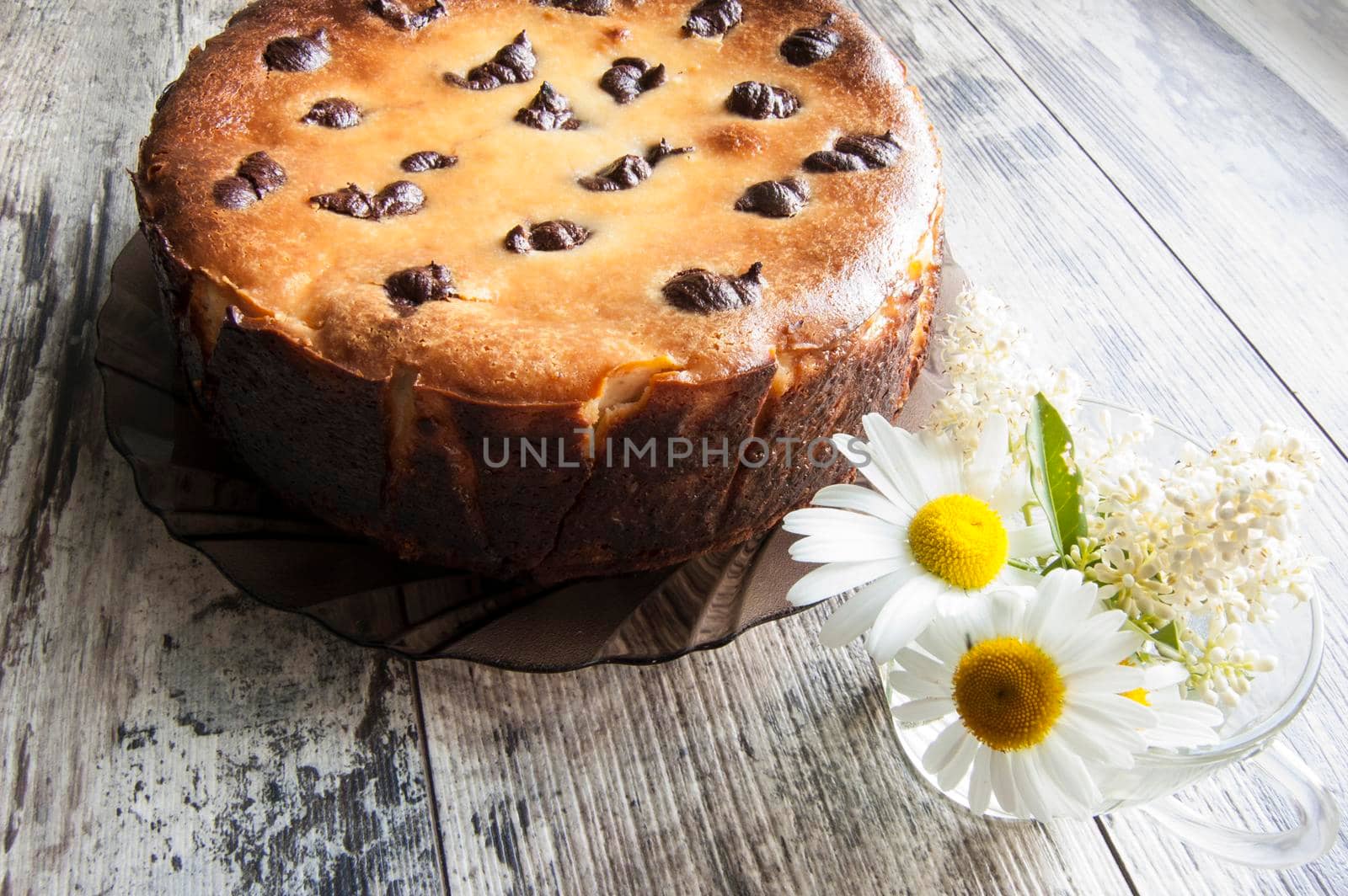 Cheesecake on an old table with a bouquet of daisies and a form for baking. Near wrapping paper. Retro style.From the series "Still Life with cheesecake"