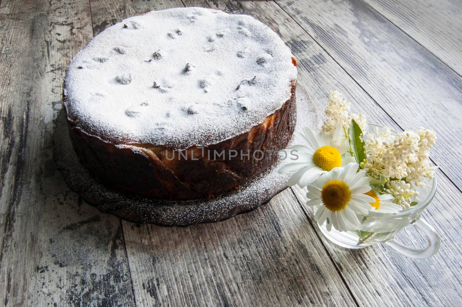 Cheesecake on an old table with a bouquet of daisies and a form for baking. Retro style. From the series "Still Life with cheesecake"