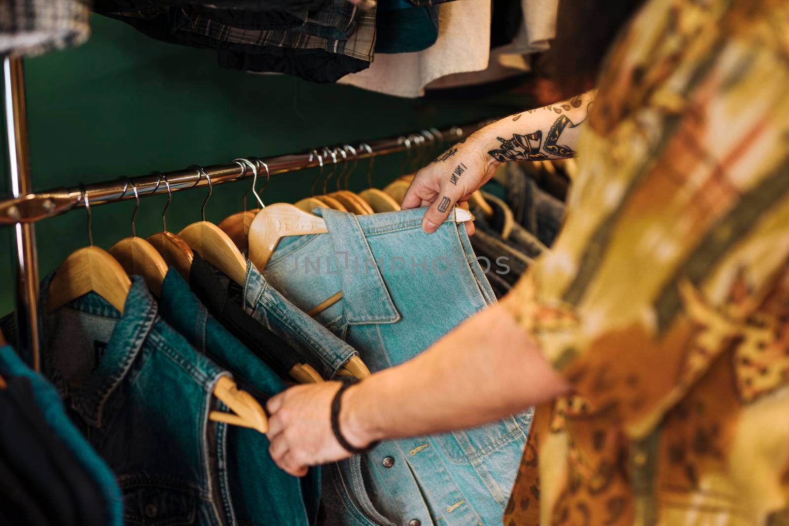 close up man s hand choosing blue jacket hanging rail clothing shop by Zahard