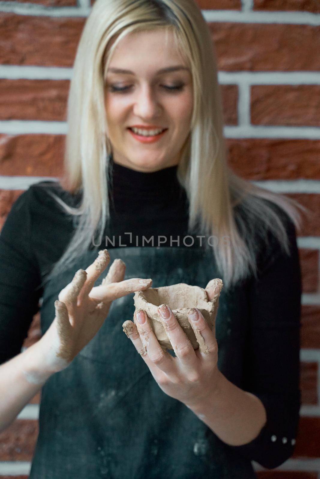 Smiling and happy woman making ceramic bowl in hand. Creative hobby concept. Earn extra money, side hustle, turning hobbies into cash, passion into a job, vertical