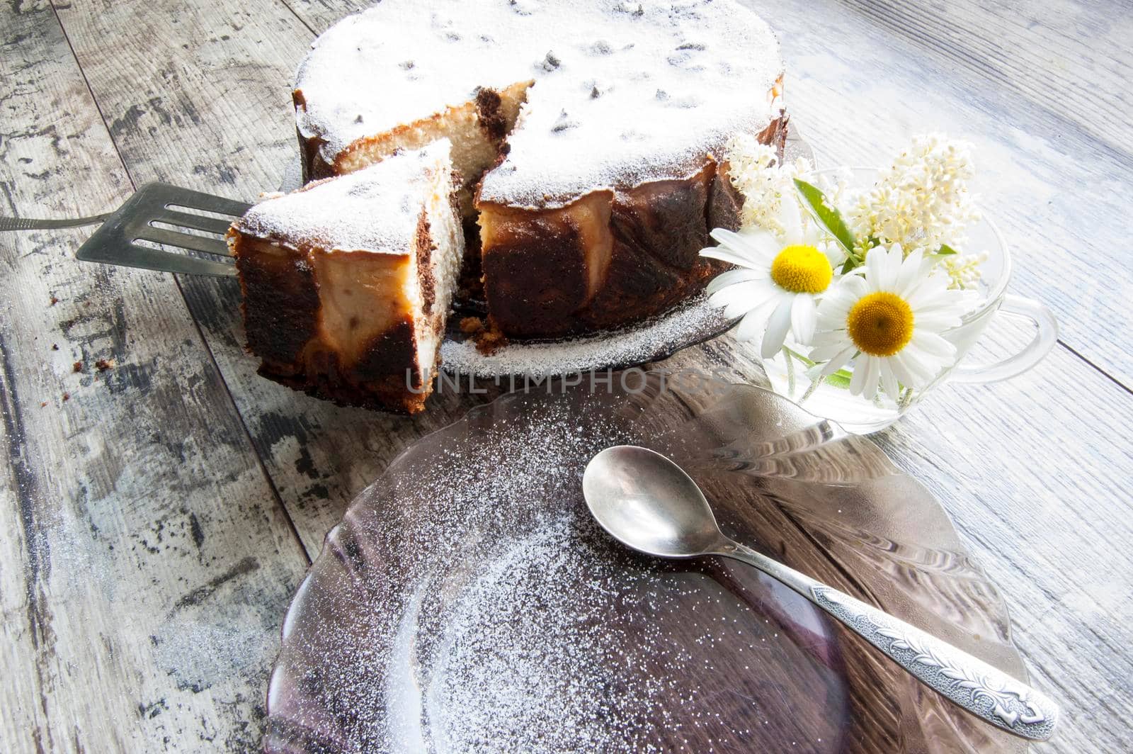 Cheesecake on an old table with a bouquet of daisies and a form for baking. Retro style. From the series "Still Life with cheesecake"