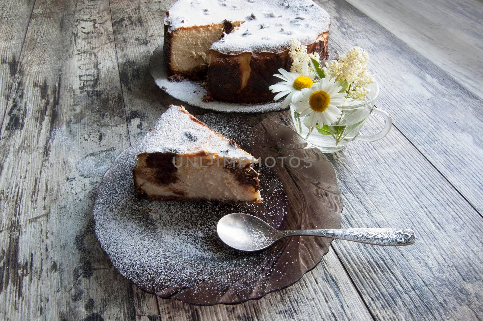 Slice of Cheesecake on an glass plate with a bouquet of daisies and a form for baking. Retro style. From the series "Still Life with cheesecake"