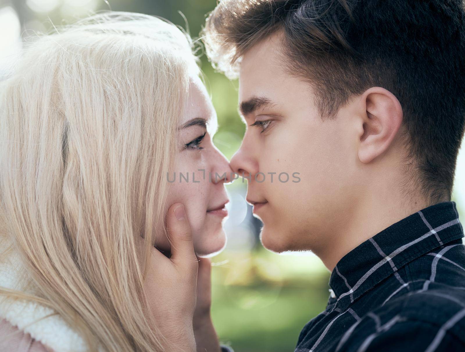 A man affectionately call looks at woman, guy and girl are worth close, touching the tips noses. Concept of teenage love and first kiss, close up