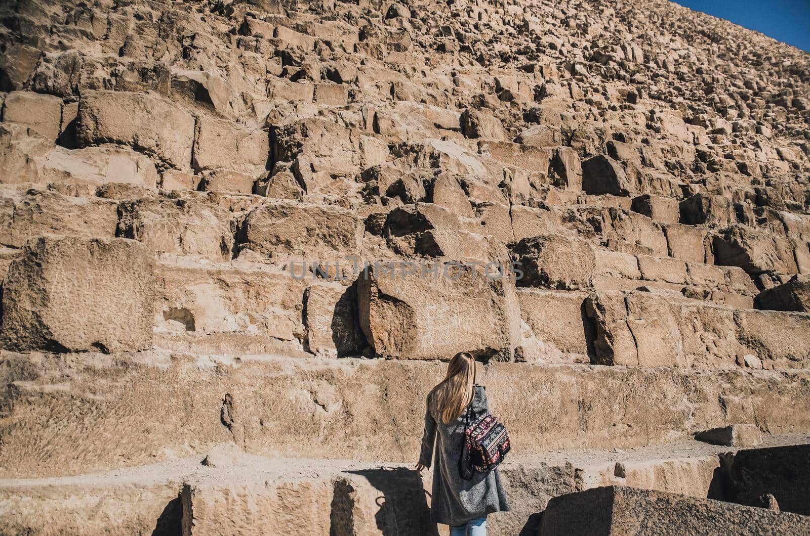 A European blonde walks near the pyramids in the desert in Cairo. The girl against the background of ancient buildings in Giza. Egyptian Sphinx