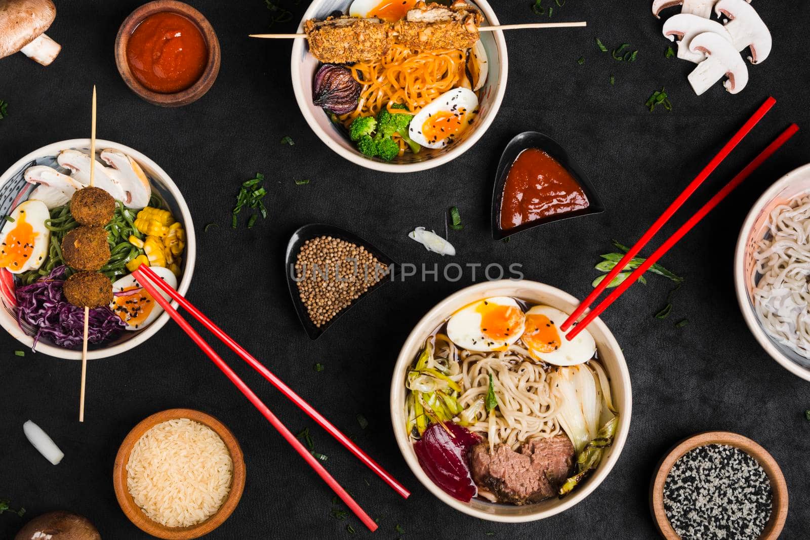 different type asian style ramen noodles with sauce rice sesame seeds black textured backdrop