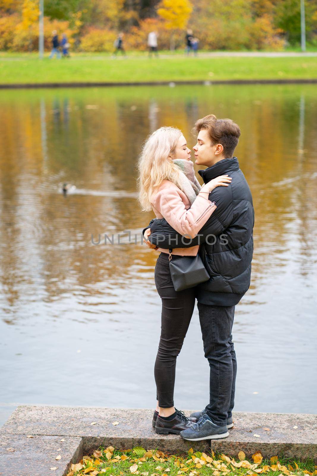 Lovely brunette guy and pretty girl blonde on date. Loving teenagers are happy, smiling, kissing. Teen Love Concept. Outdoor, vertical