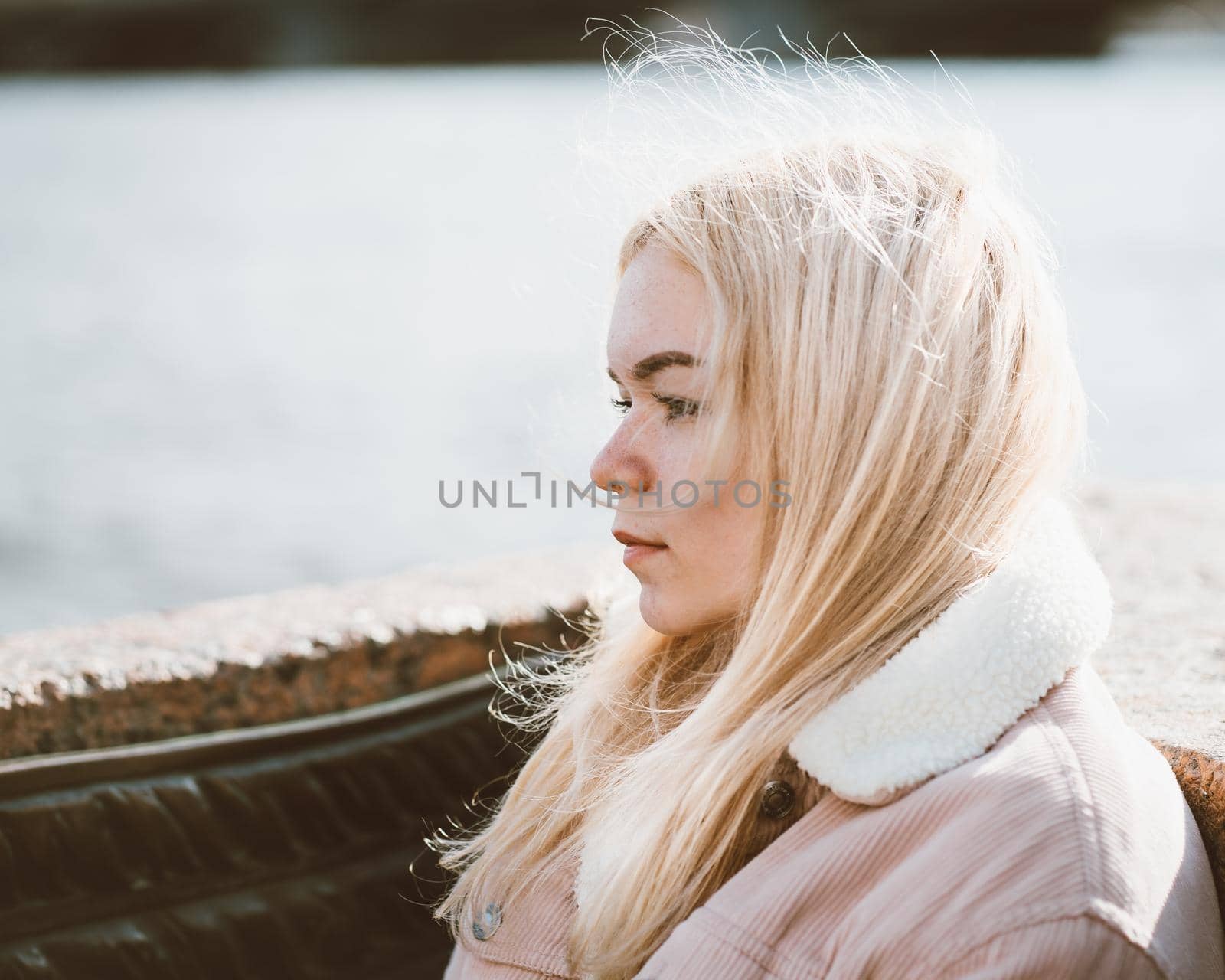 Portrait of a young girl, blonde with bleached hair, Caucasian. Scandinavian style. Close - up of a teenage woman looking past a camera in the city near the water.