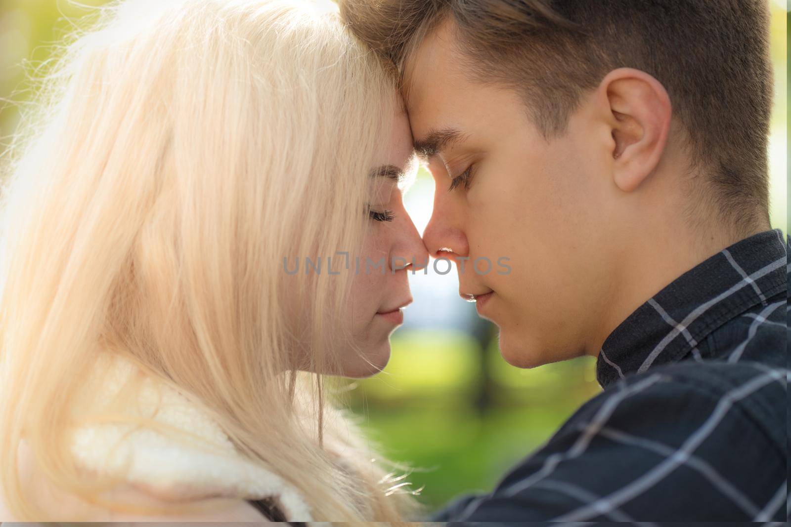 A man affectionately call looks at woman, guy and girl are worth close, touching the tips noses. The concept of first teenage love and a first kiss. Boy and girl, couple. Intimacy, honesty, trust, open feelings. Close up portrait.