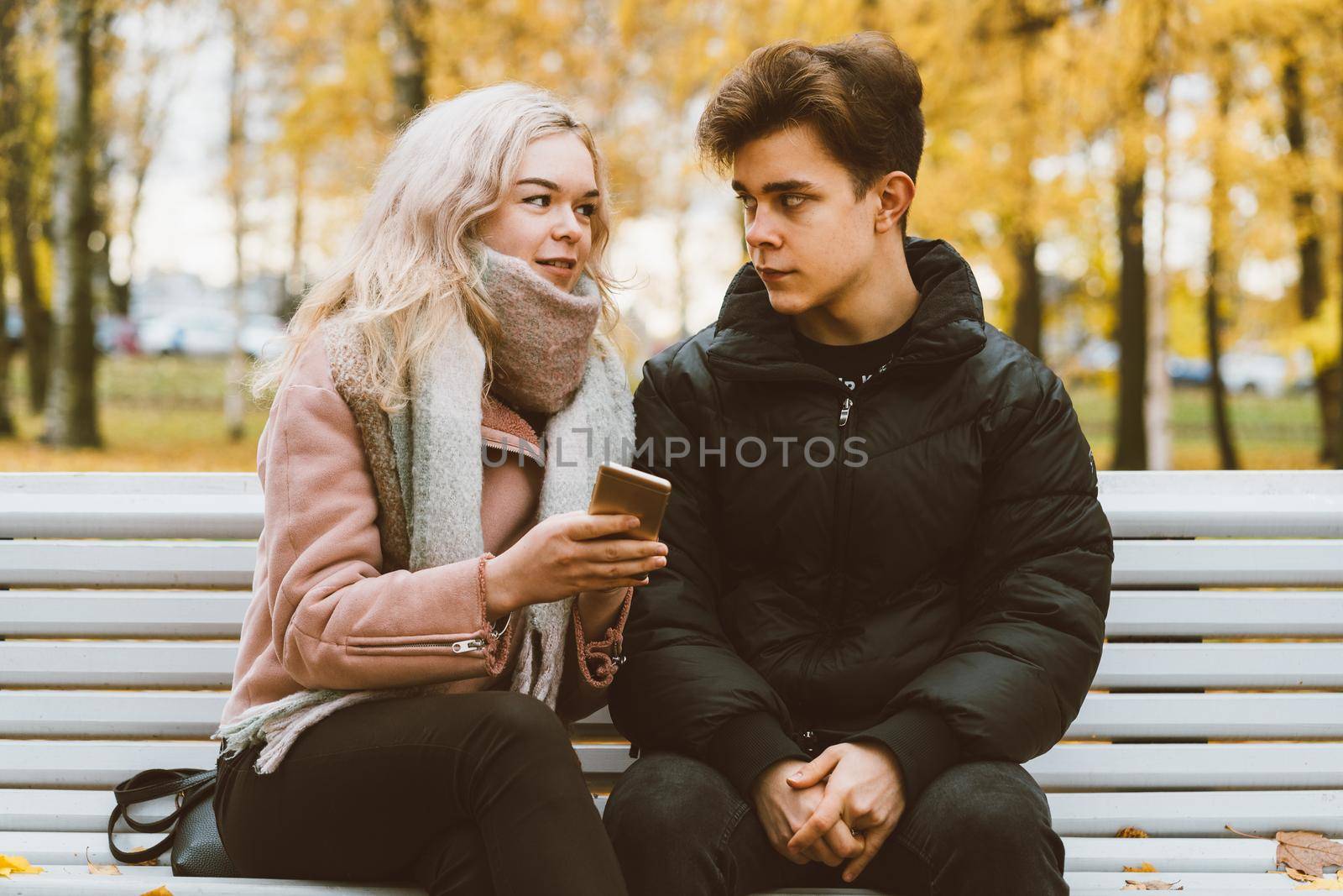 Young beautiful blonde girl blames her boyfriend by pointing finger to the phone screen. The concept of jealousy, quarrels, difficulties in communicating through social networks