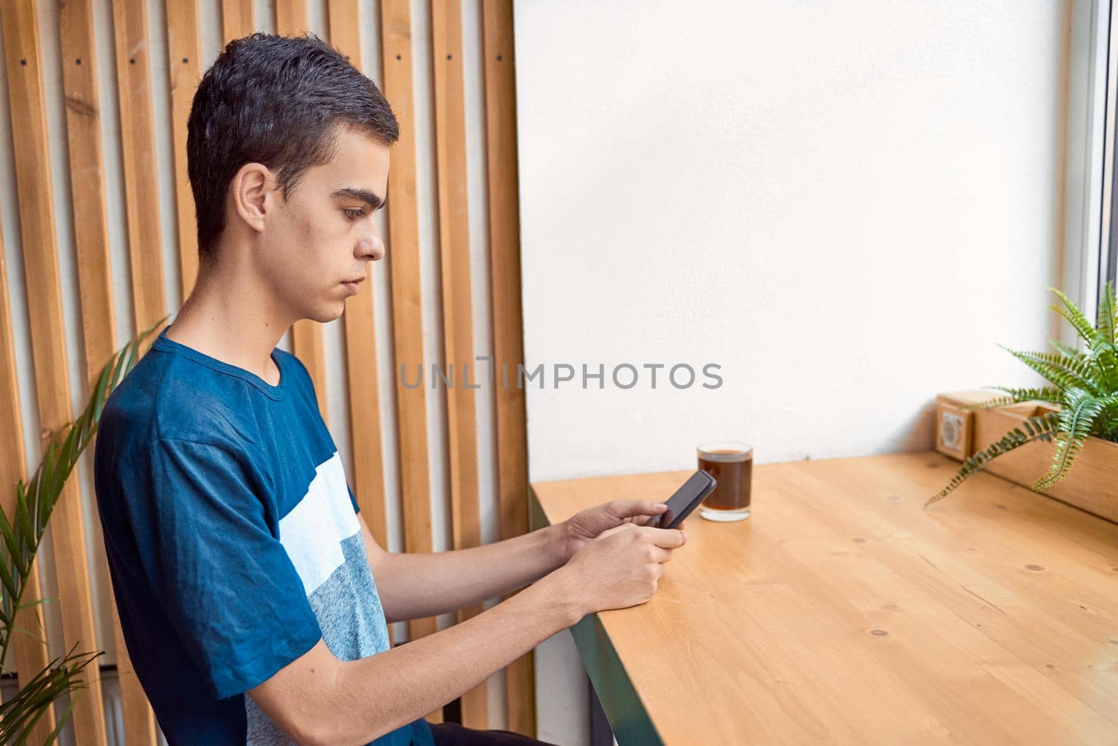 Young adult looking at the phone, sitting in a cafe. Digital age. People communicate in chat, copy space