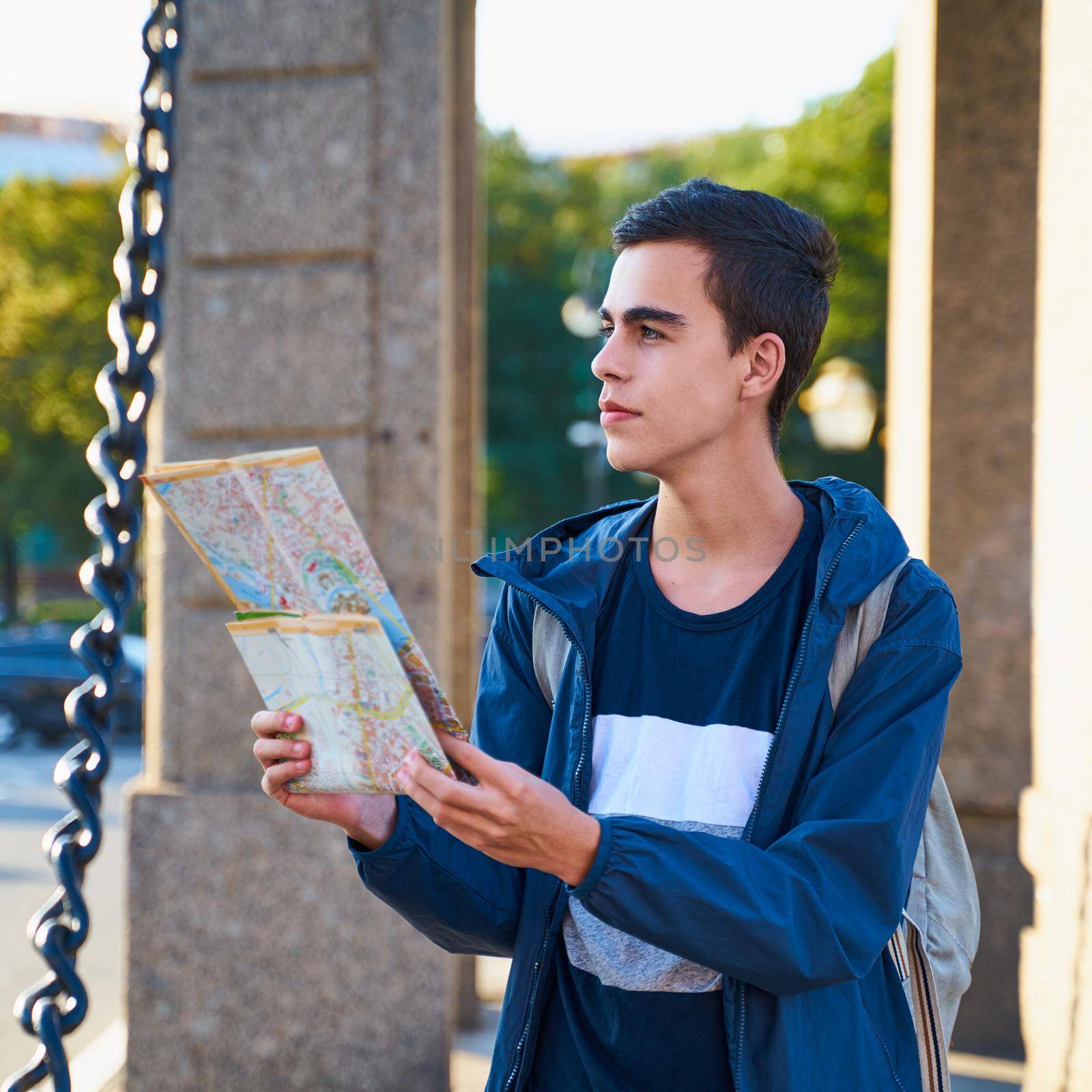 young man standing on the street of a big city and looking at the guide, a tourist in St. Petersburg looking for a route