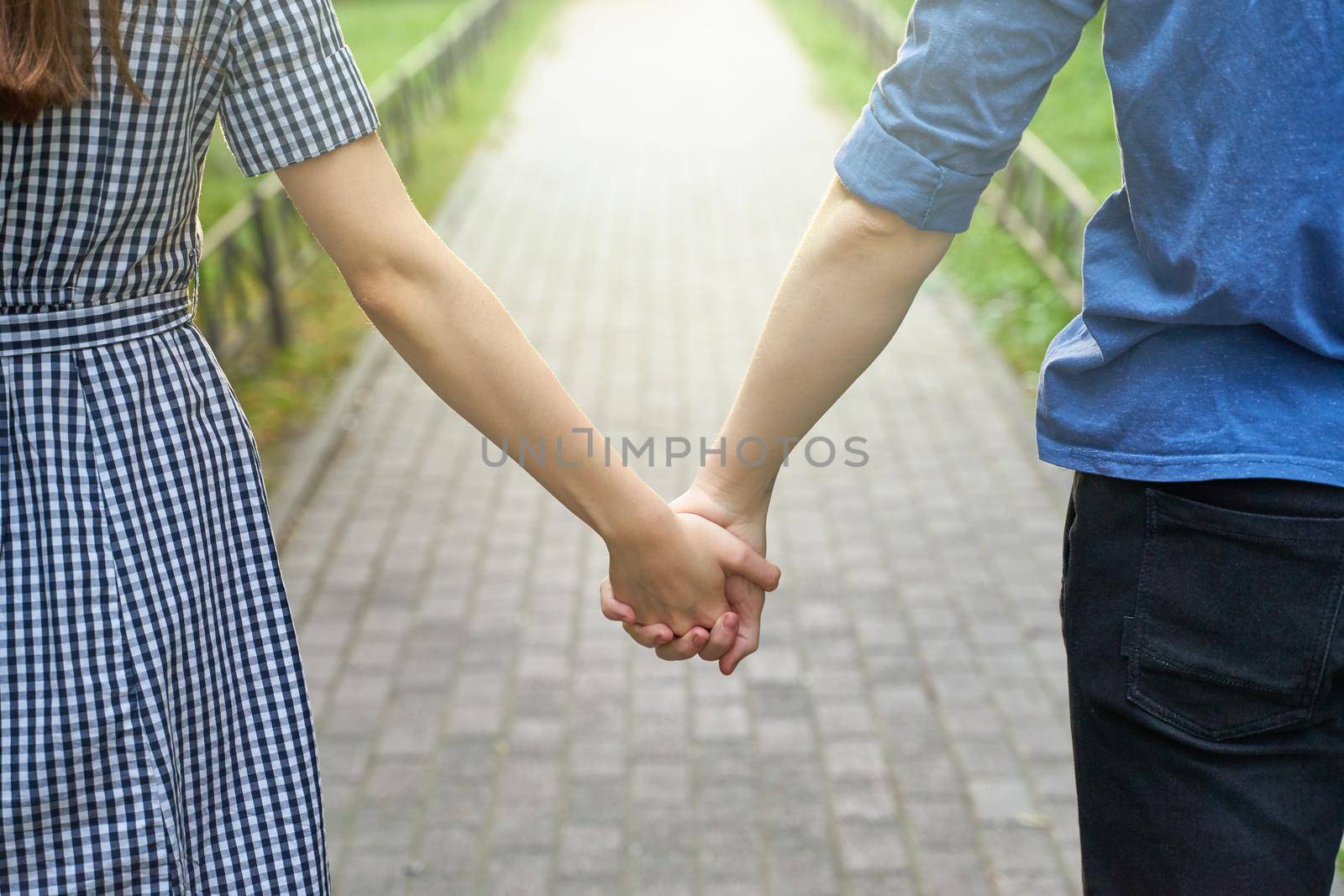 Couple holding hands while walking in the park closeup by NataBene