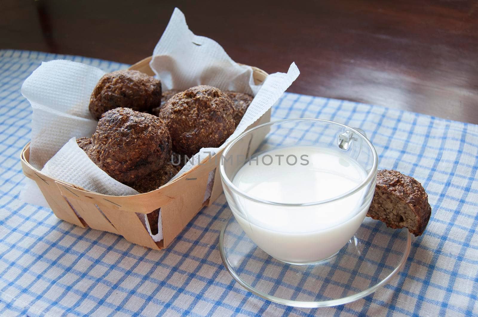 Glass cup of milk on an old table. Near basket with fresh bread