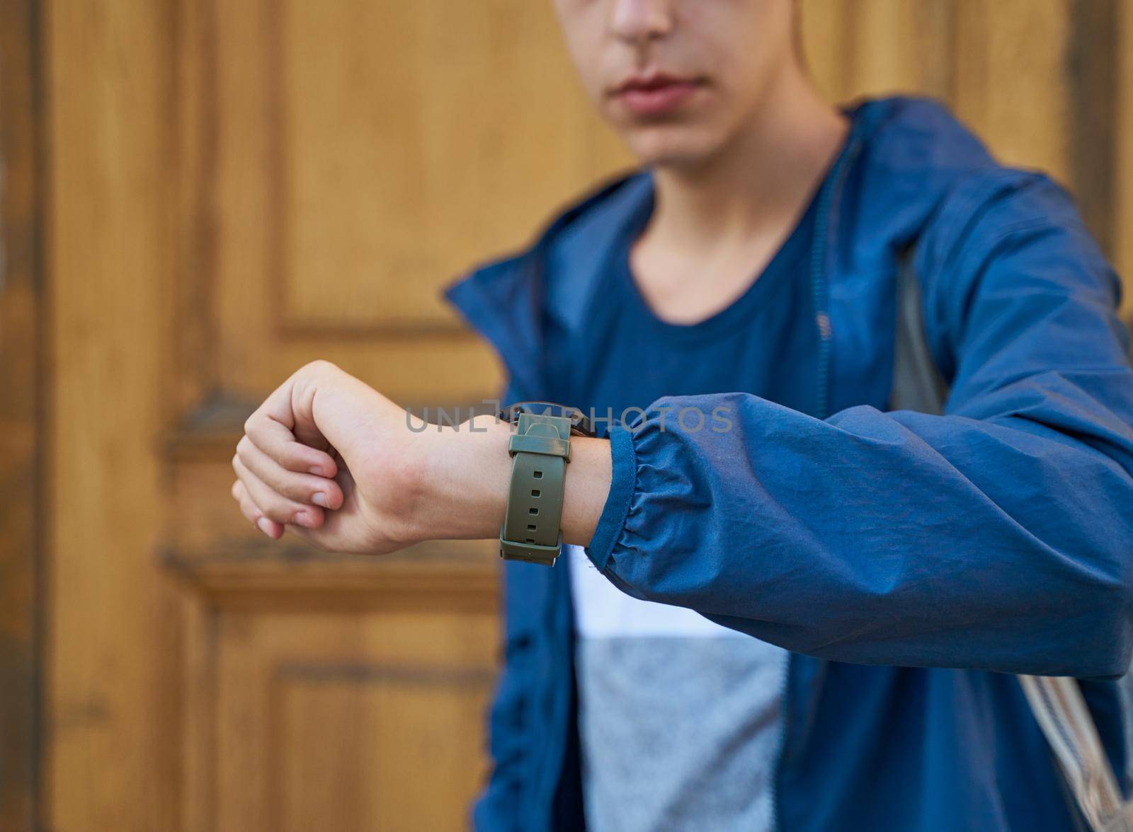 Young adult looks at the clock, waiting for a meeting with friends. A man is waiting for a woman in a street of city on a date, looking at the watch, copy space, close up