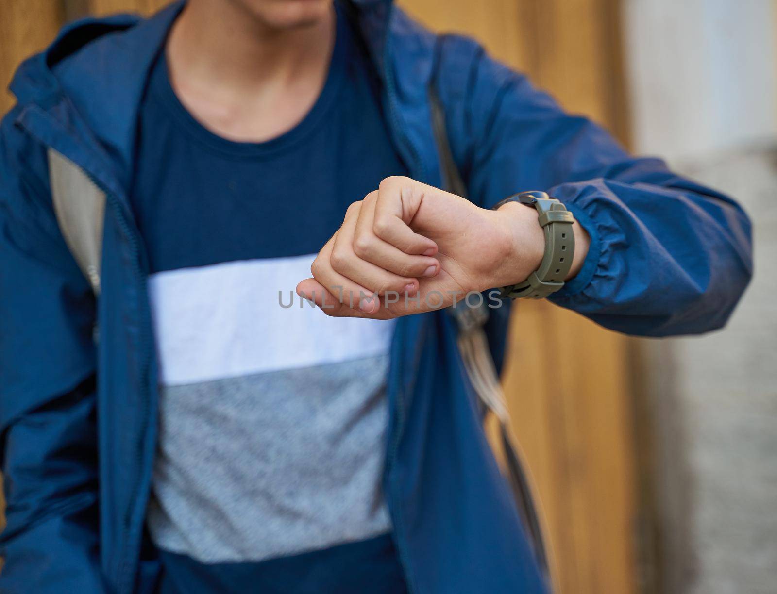 Young adult looks at the clock, waiting for a meeting with friends. A man is waiting for a woman in a street of city on a date, looking at watch by NataBene