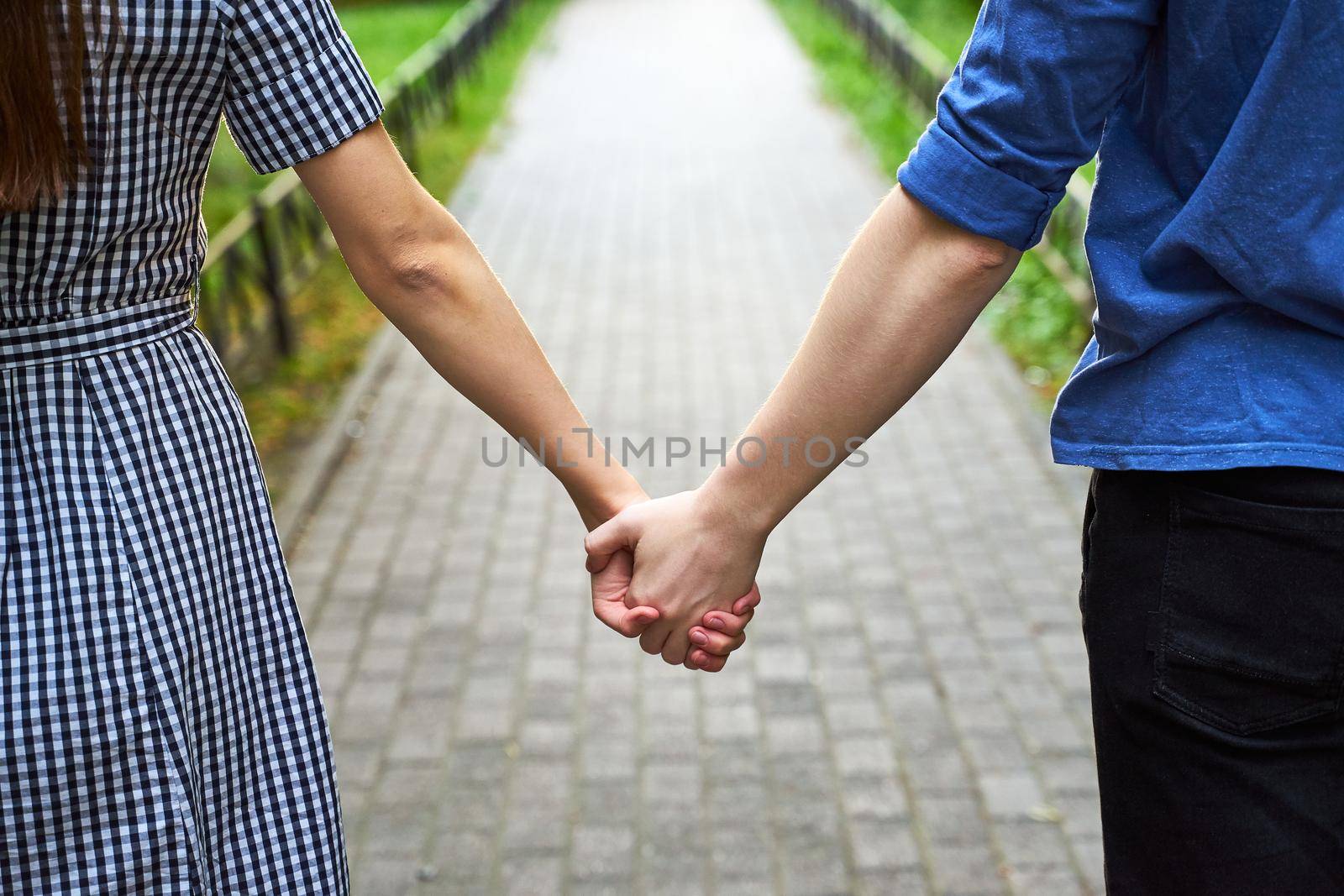 Closeup of loving couple holding hands while walking in the park by NataBene