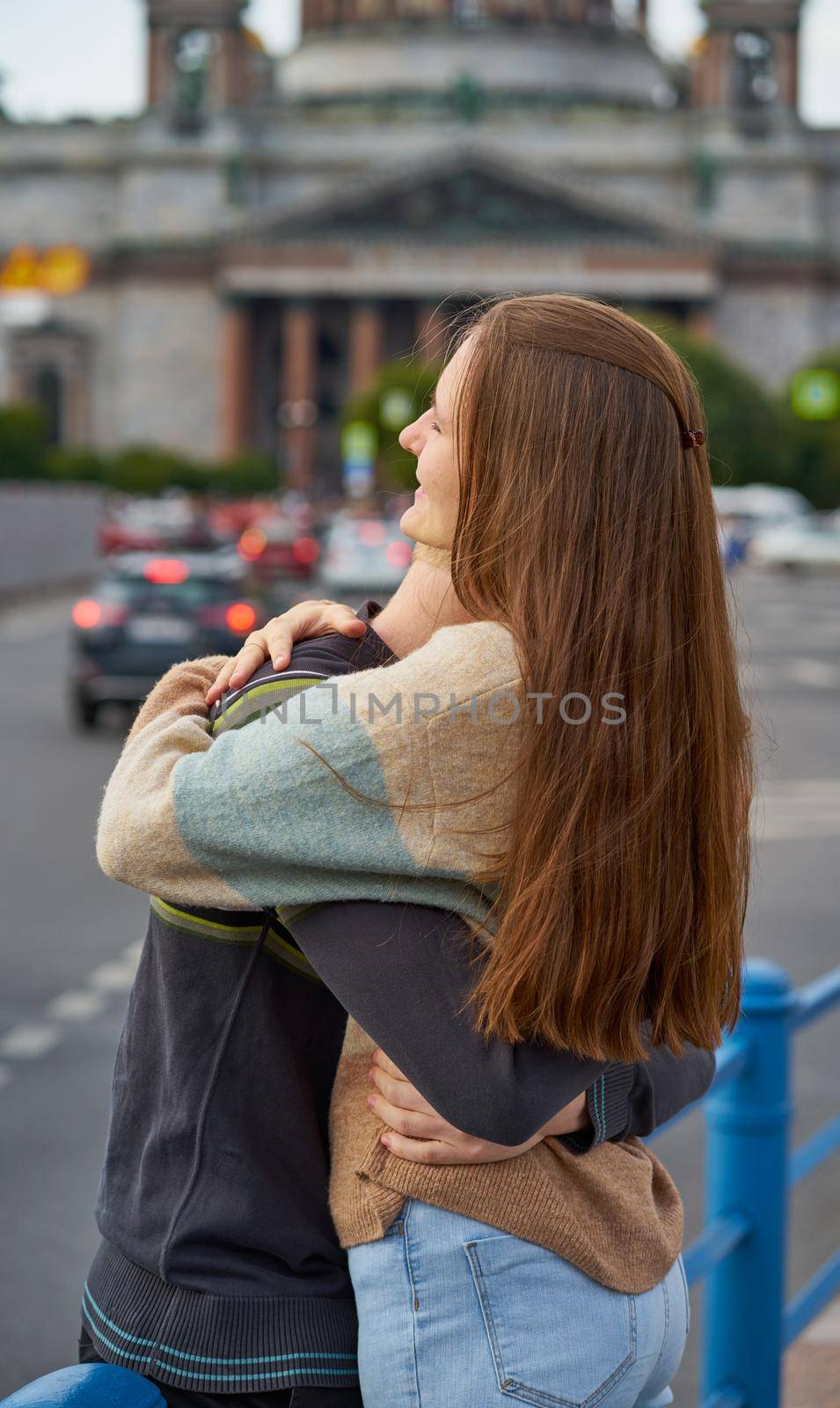 Girl with long thick dark hear embracing redhead boy in the blue t-shirt on bridge, teen love, vertical