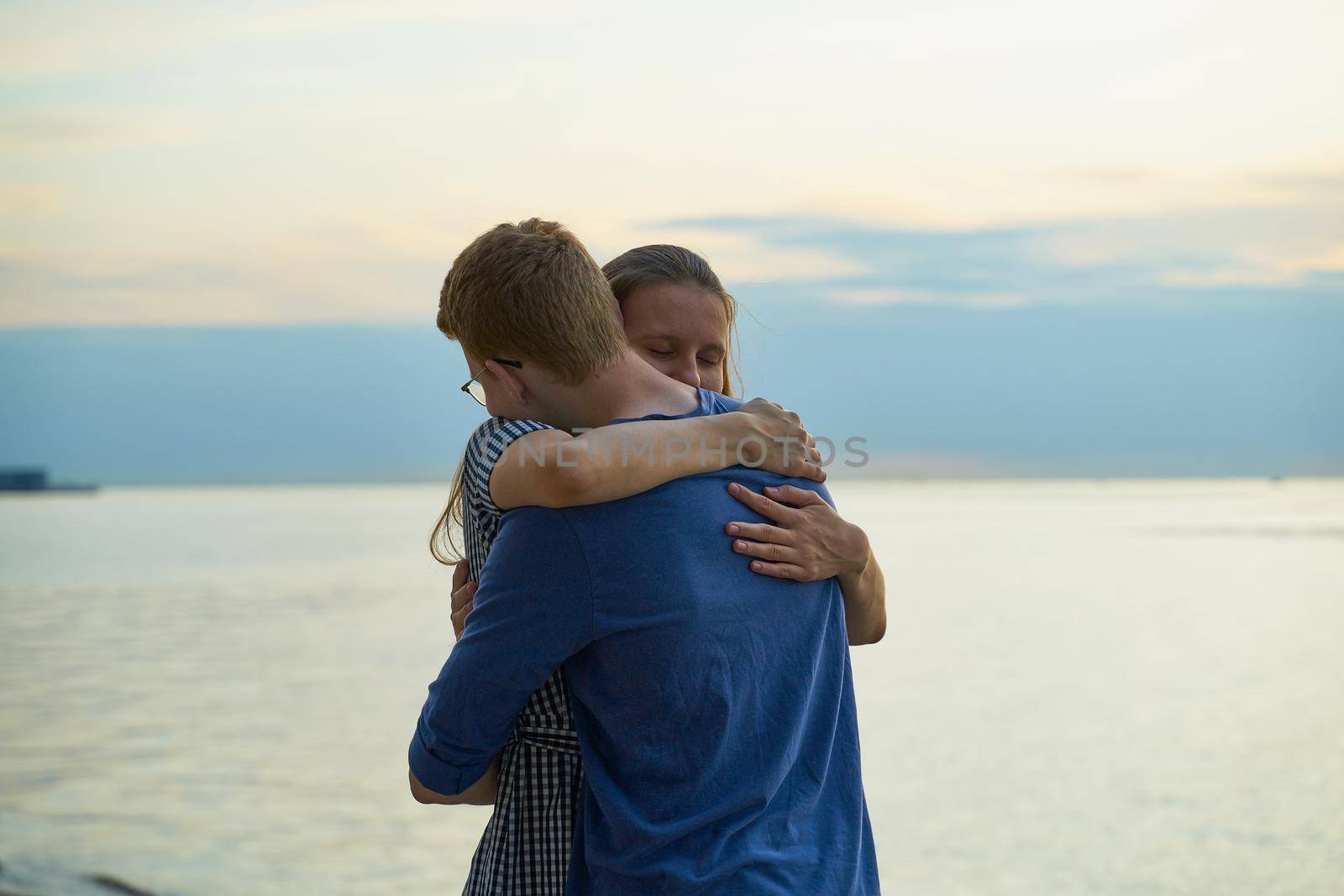 Girl embracing boy on beach, teen love at the sunset, copy space by NataBene