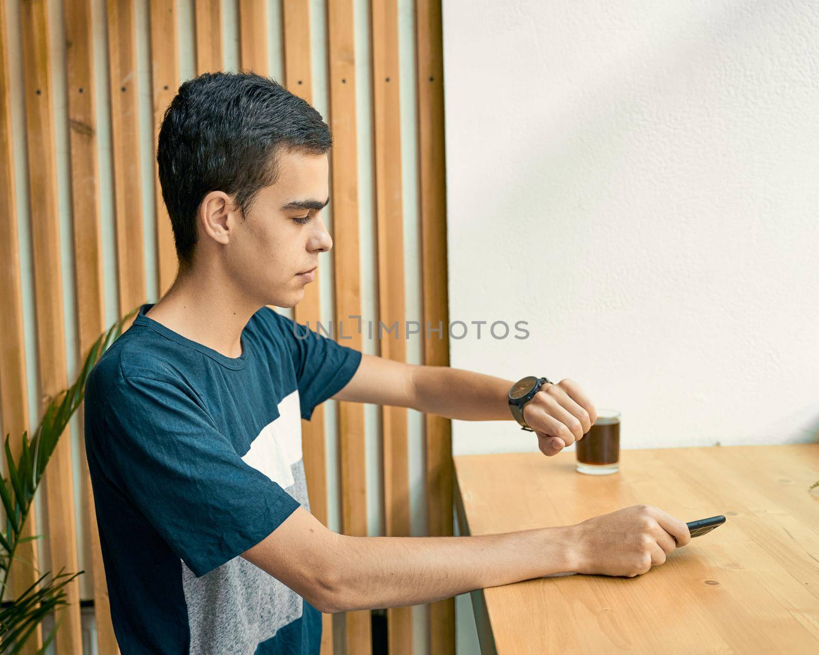 Young adult looks at the clock, waiting for a meeting with friends. A man is waiting for a woman in a cafe on a date, looking at the watch, copy space