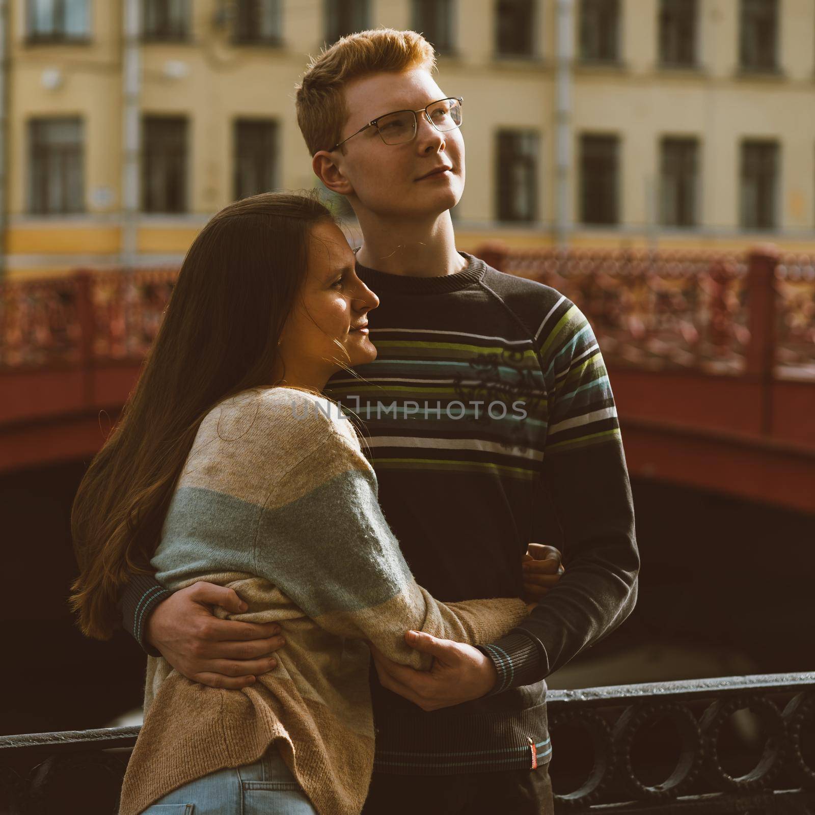Man and woman stand on a bridge in the center of the city and look up in one direction. Boy and girl dream and think. The concept of teenage love, the first serious relationship, the difficulties of adolescence by NataBene