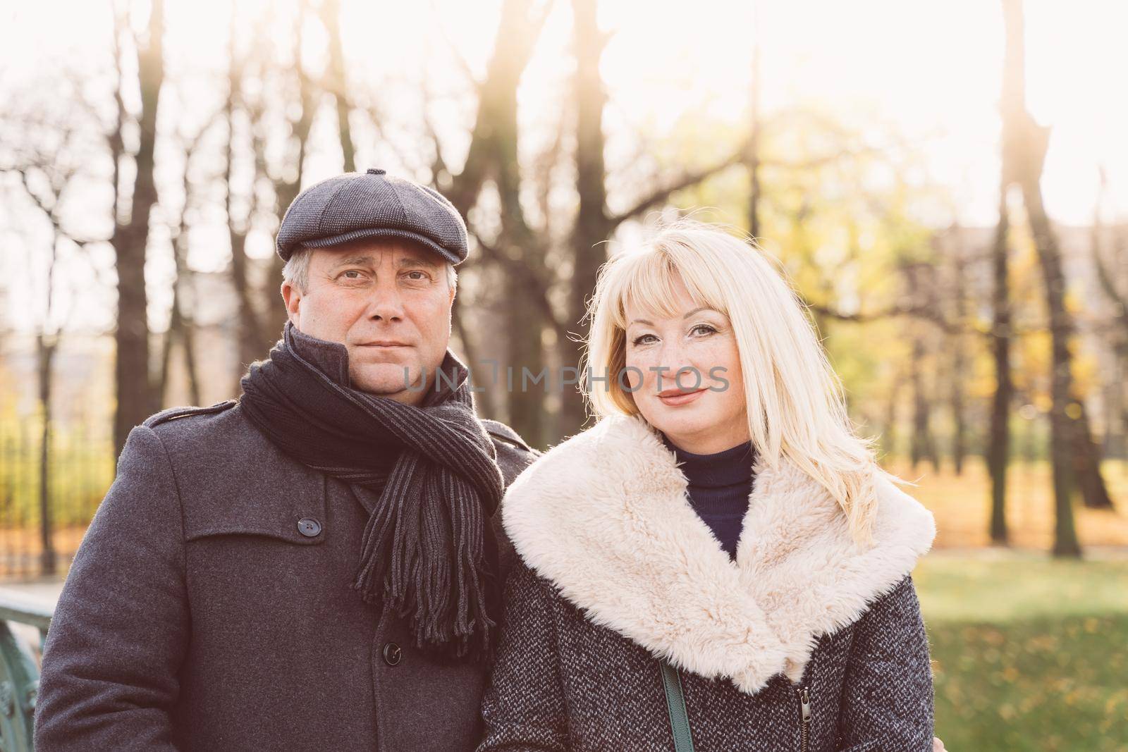 Closeup portrait of happy blonde mature woman and beautiful middle-aged brunette, looking looking directly at the camera. Loving couple of 45-50 years old walks in autumn park in warm clothes