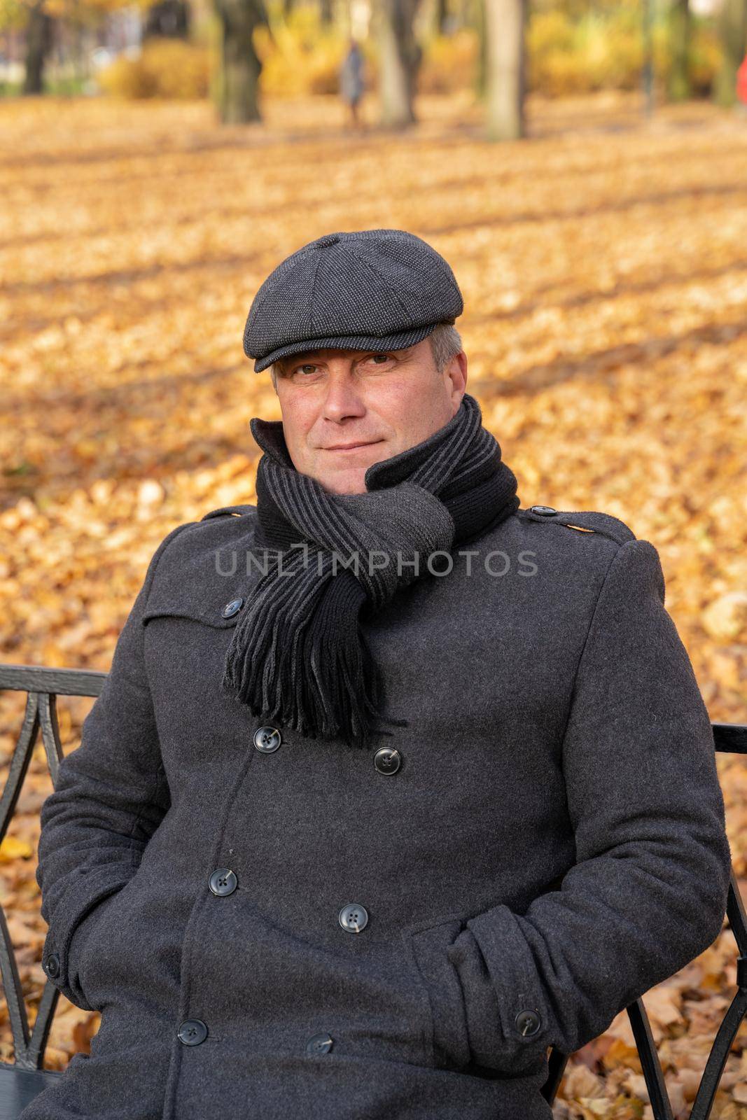 Closeup portrait of a beautiful middle-aged brunette. Mature handsome man of 45-50 years old walks in the autumn park in warm clothes, in a coat and enjoys life