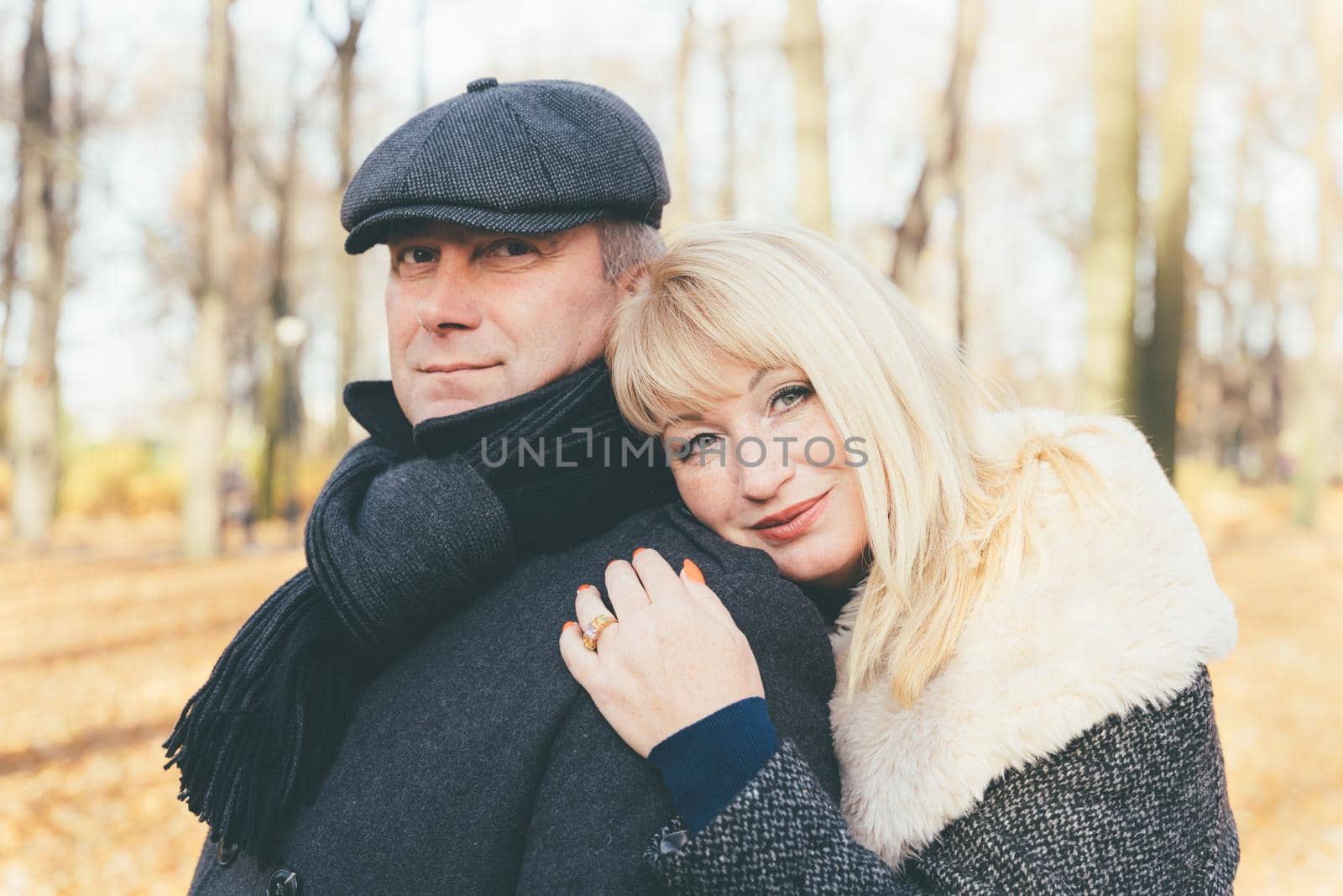 Closeup portrait of happy blonde mature woman and beautiful middle-aged brunette, looking directly at the camera. Loving couple of 45-50 years old walks in autumn park in a warm clothes