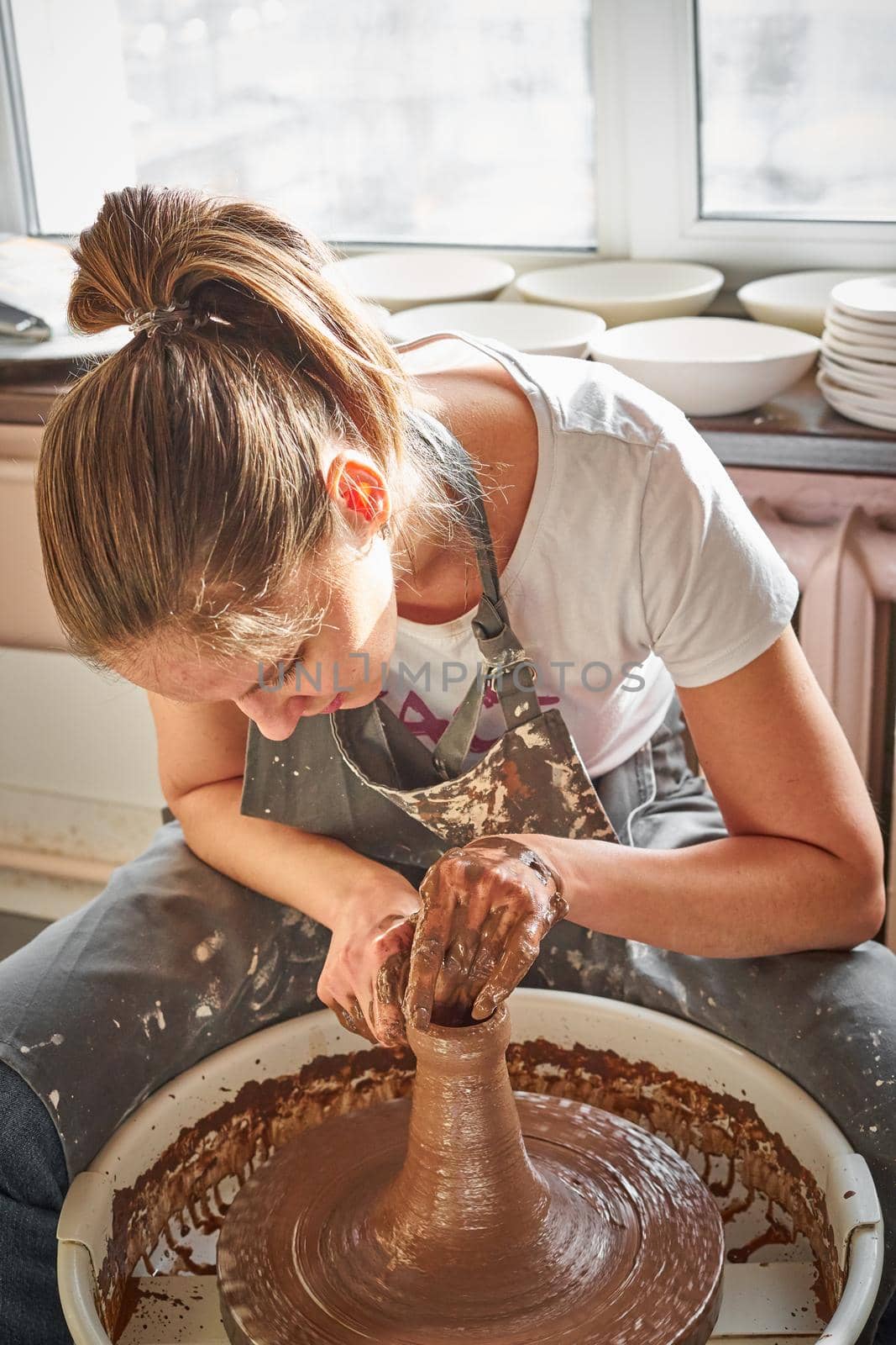 Beautiful woman making ceramic pottery on wheel, hands close-up. Concept for woman in freelance, business, hobby