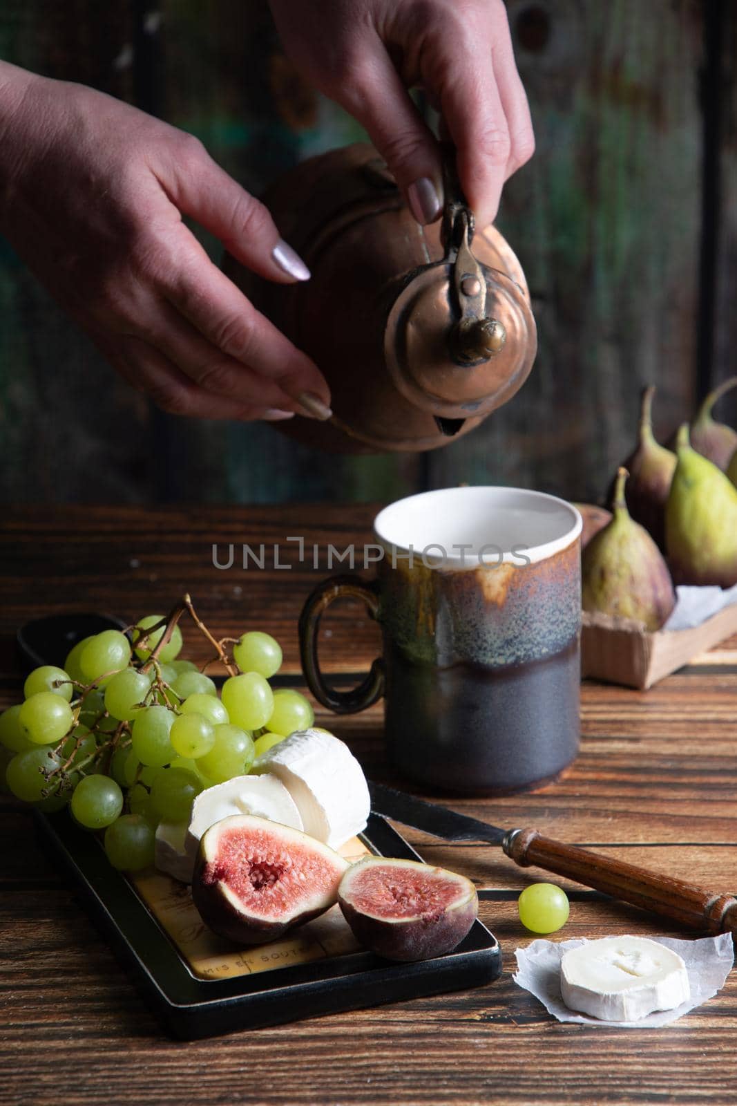 cheese plate with goat cheese, grapes and figs, copper teapot, angle view, healthy food, high-calorie breakfast. High quality photo