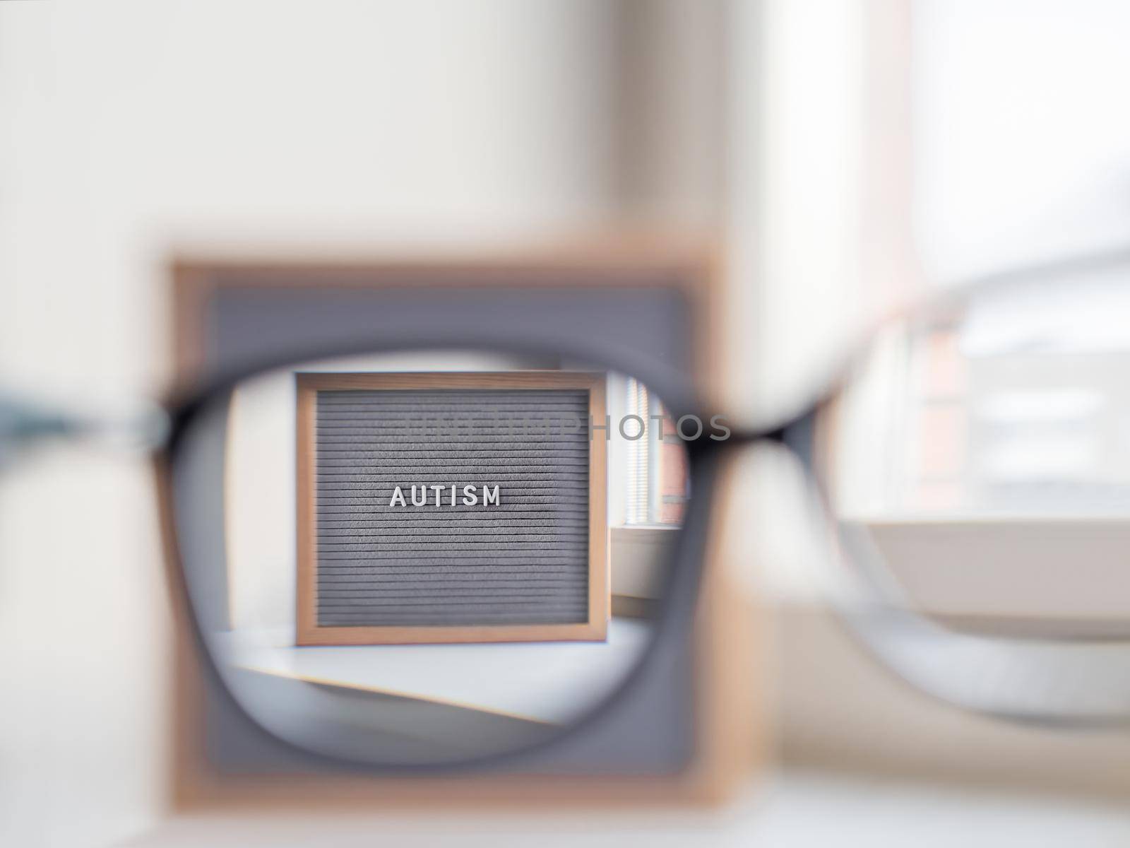 Grey letterboard with word Autism. View through eyeglasses on medical diagnosis which usually made in childhood. Drawing attention to development of children.