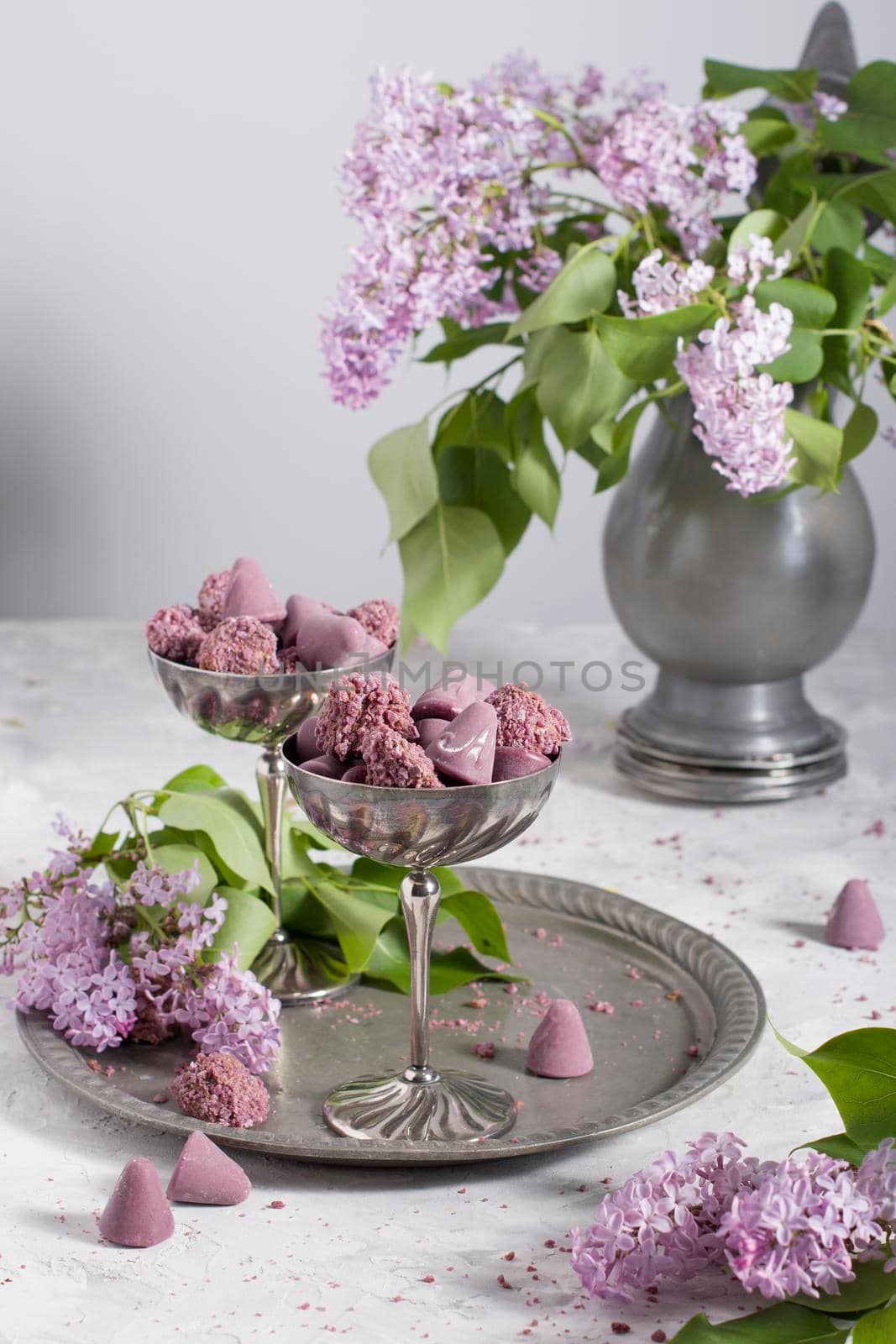 Belgian sweets cuberdon and pralines in silver glasses, spring still life,lilac . High quality photo