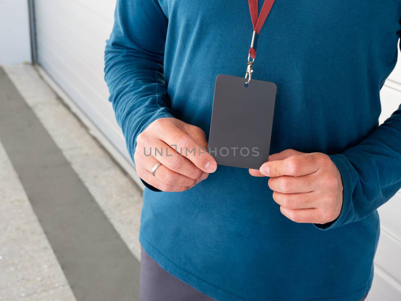 Man with badge near garage. Close up photo of hands with clear black name tag.