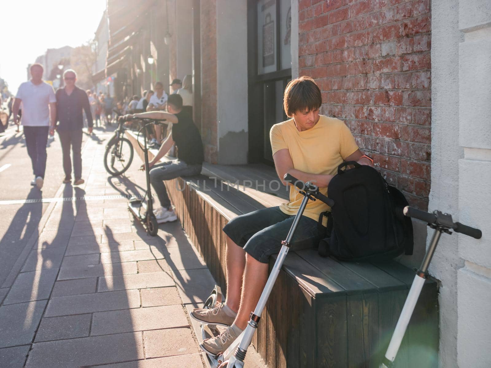 MOSCOW, RUSSIA - June 13, 2021. Man sits with kick scooter in street cafe. Modern lifestyle. Summer vibes. Open air workplace. Street life.