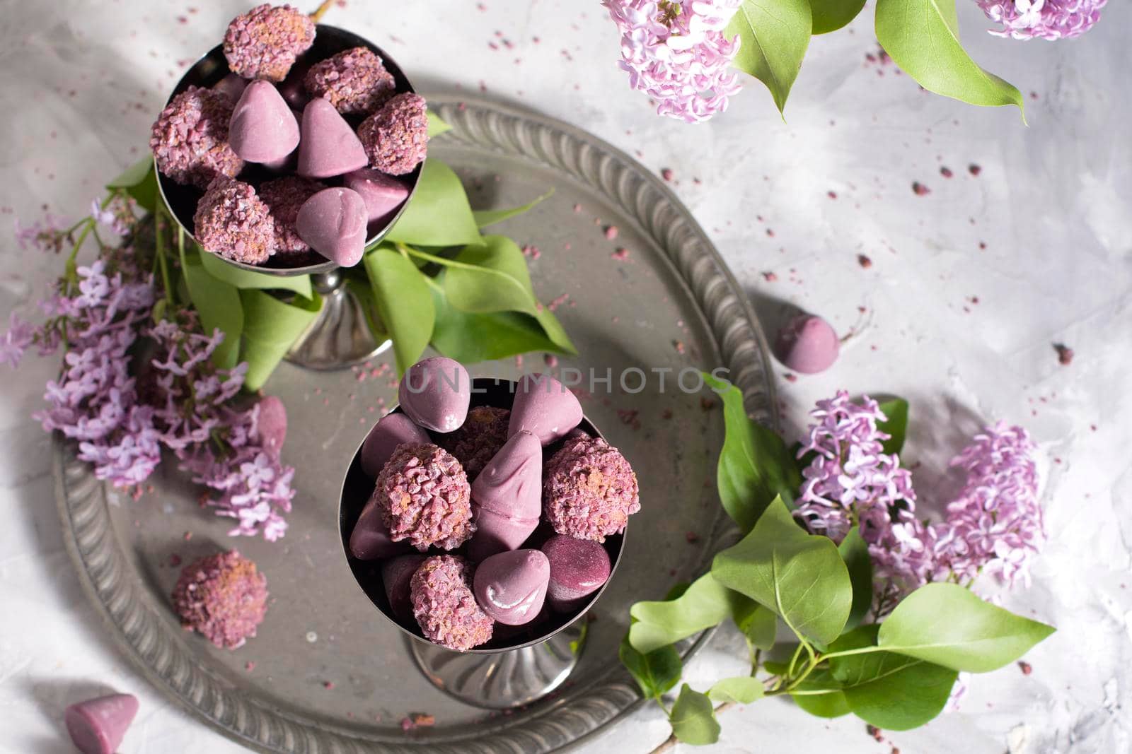 Belgian sweets cuberdon and pralines in silver glasses, spring still life,lilac . High quality photo