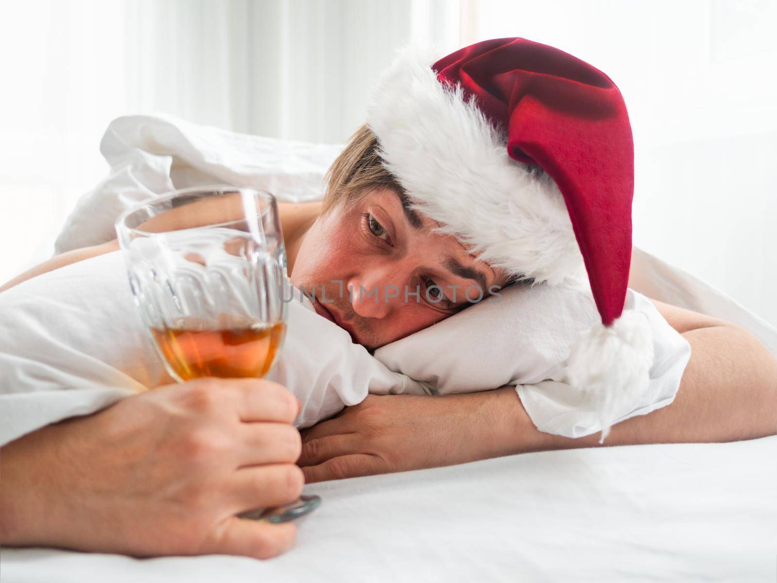 Man in Santa hat is trying to freshen the nip after alco party. He is suffering of headache after New Year or Christmas celebration. Heavy morning. Alcohol withdrawal. Worst hangover. by aksenovko