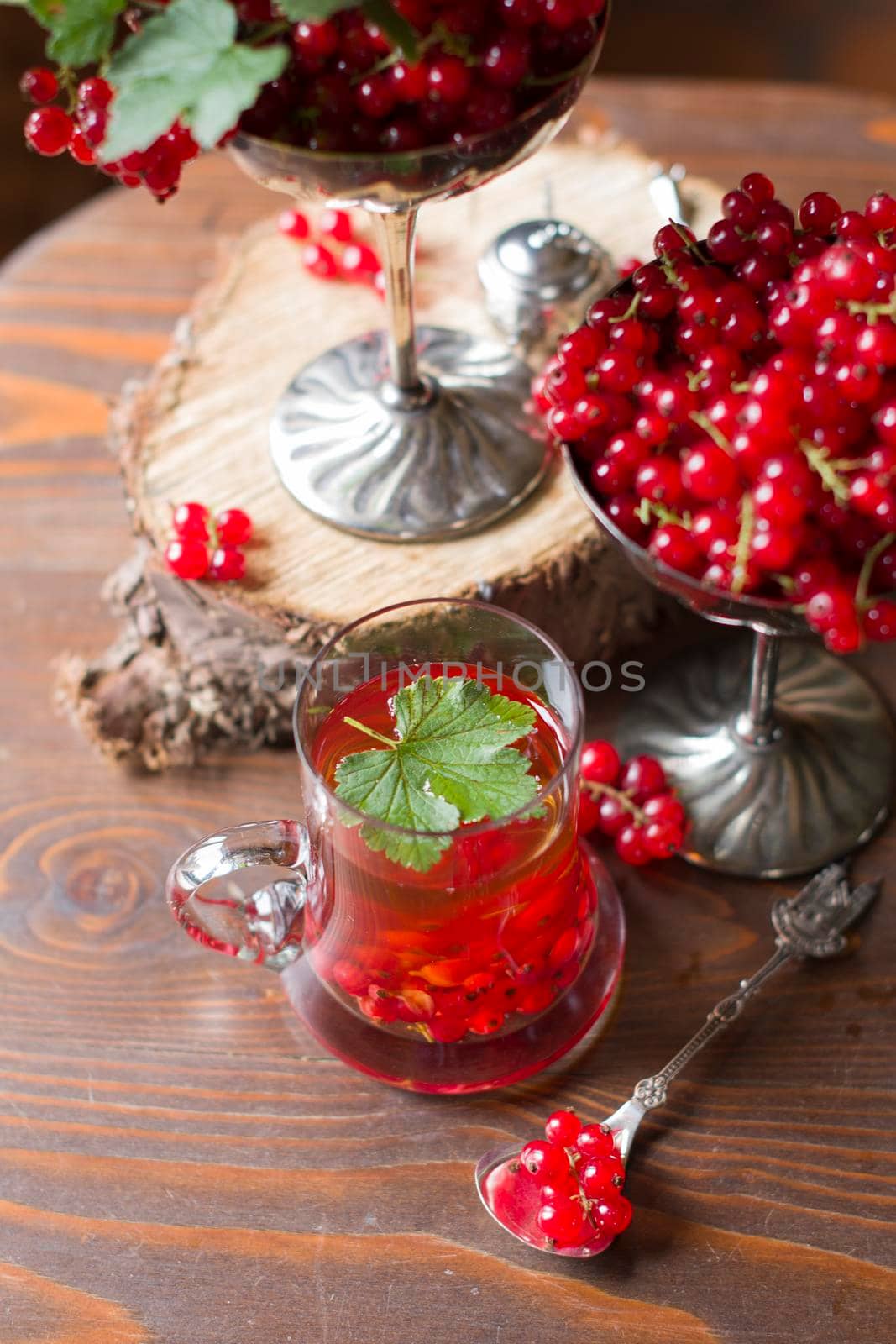 Fruit still life with a bouquet of red currant branches and tea in a transparent glass, natural food, vegetarian tea, summer berry picking