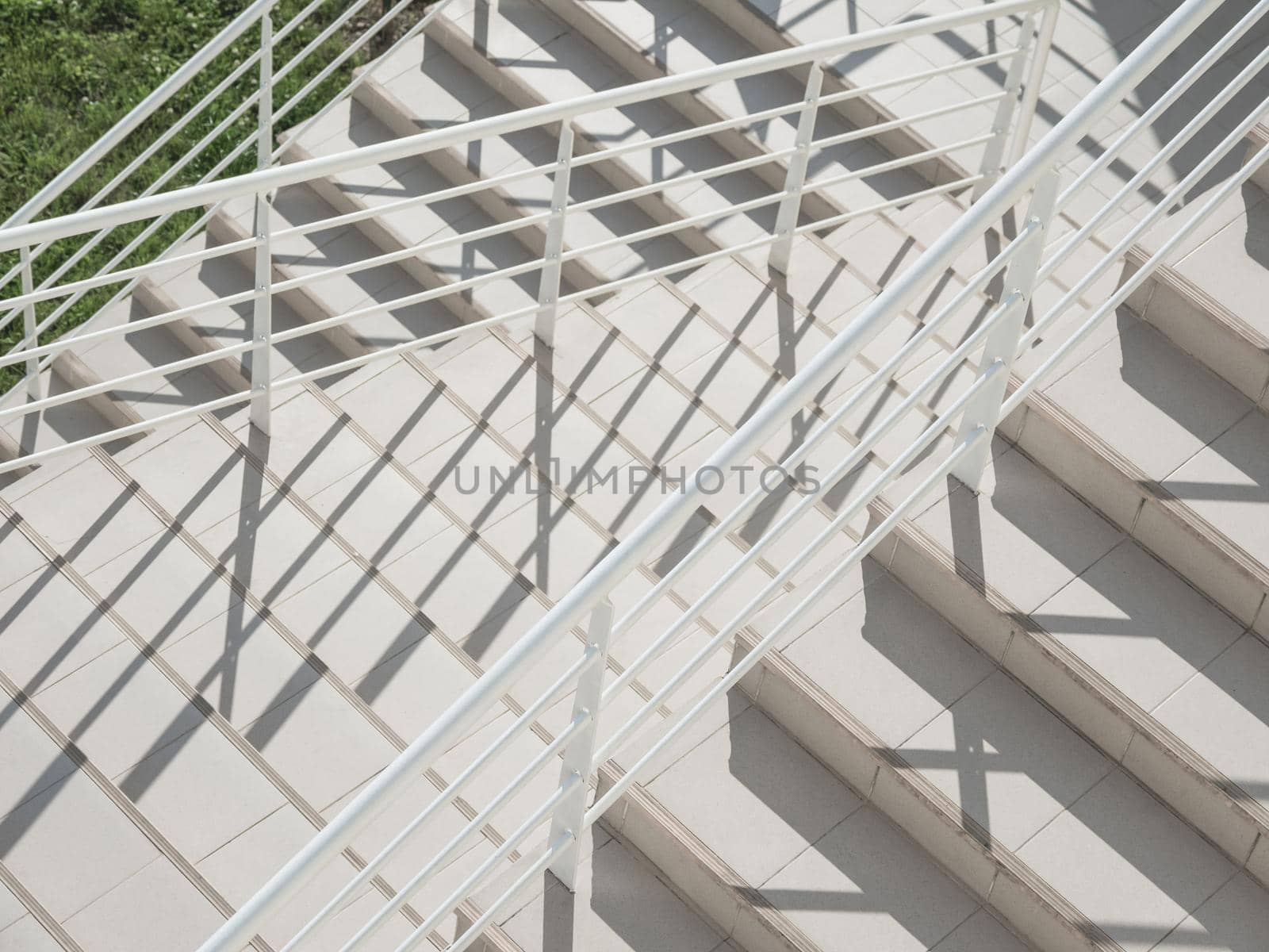 White exterior of outdoor staircase with railing. Sunlight and shadow on stone steps. Urban geometry. by aksenovko