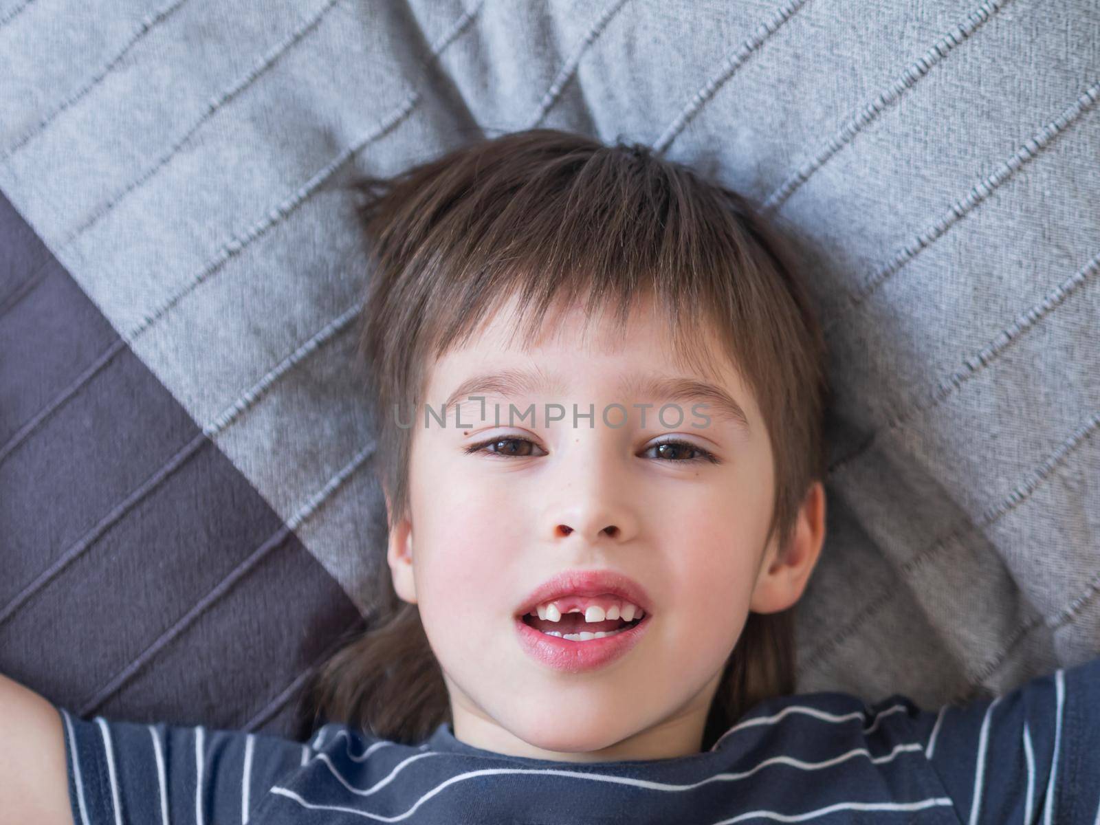 Smiling kid shows hole in row of teeth in his mouth. One incisor fell out just now. Close up photo of gums for dentist.