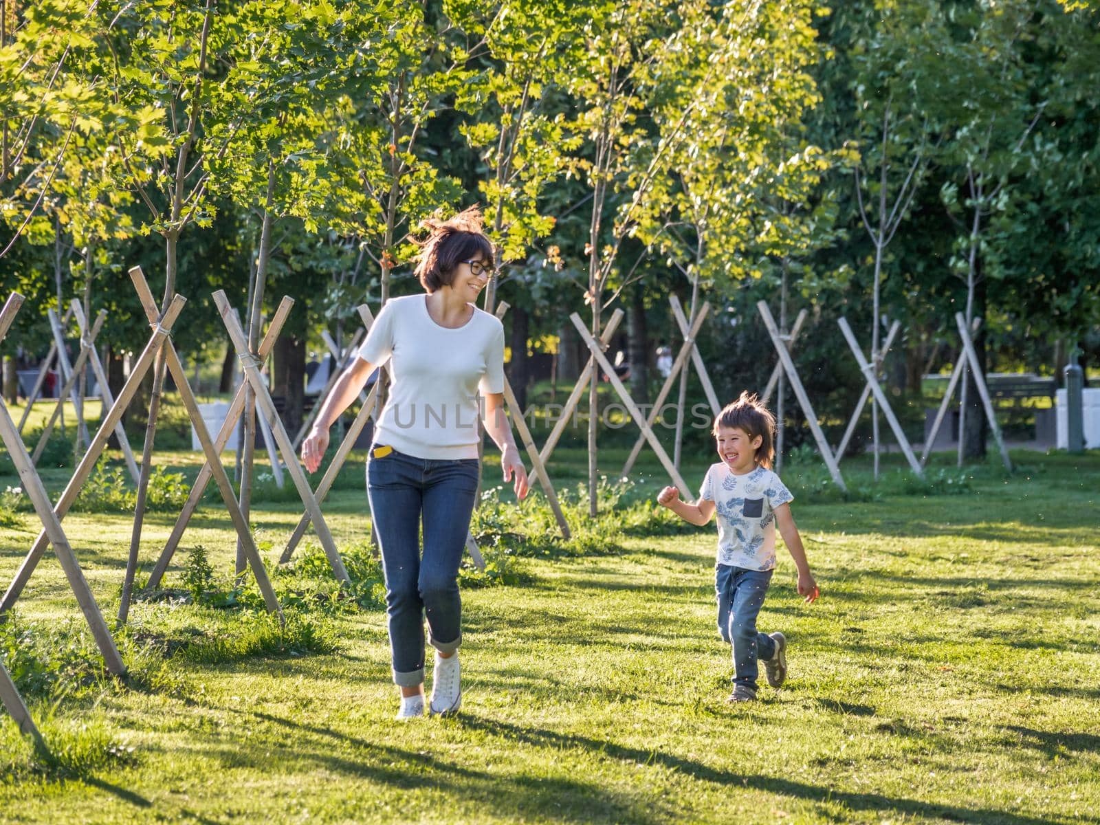 Family life. Mother and son play in park. Summer vibes. Active outdoor game. Lifestyle. Leisure activity open air. by aksenovko