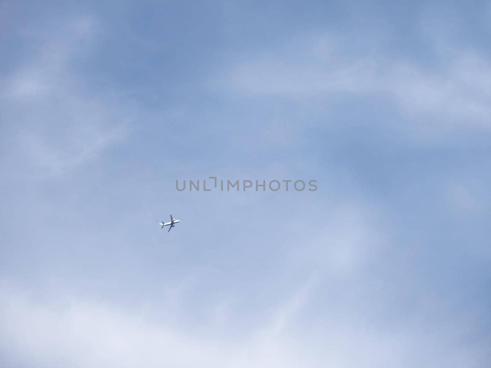 Airplane is flying in clear blue sky. Aircraft in flight in good weather. Minimalism. by aksenovko